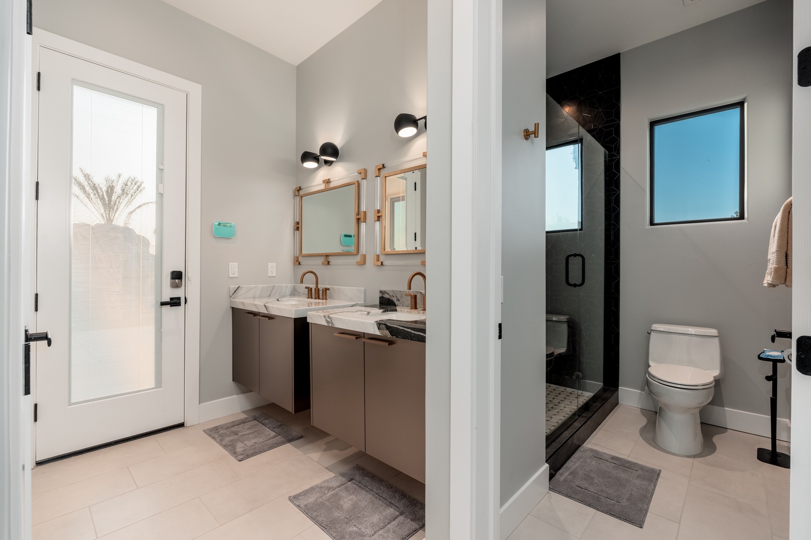 Modern bathroom with dual marble vanities, stylish rose gold fixtures, and a sleek walk-in shower. Fresh towels and natural light create your personal retreat.