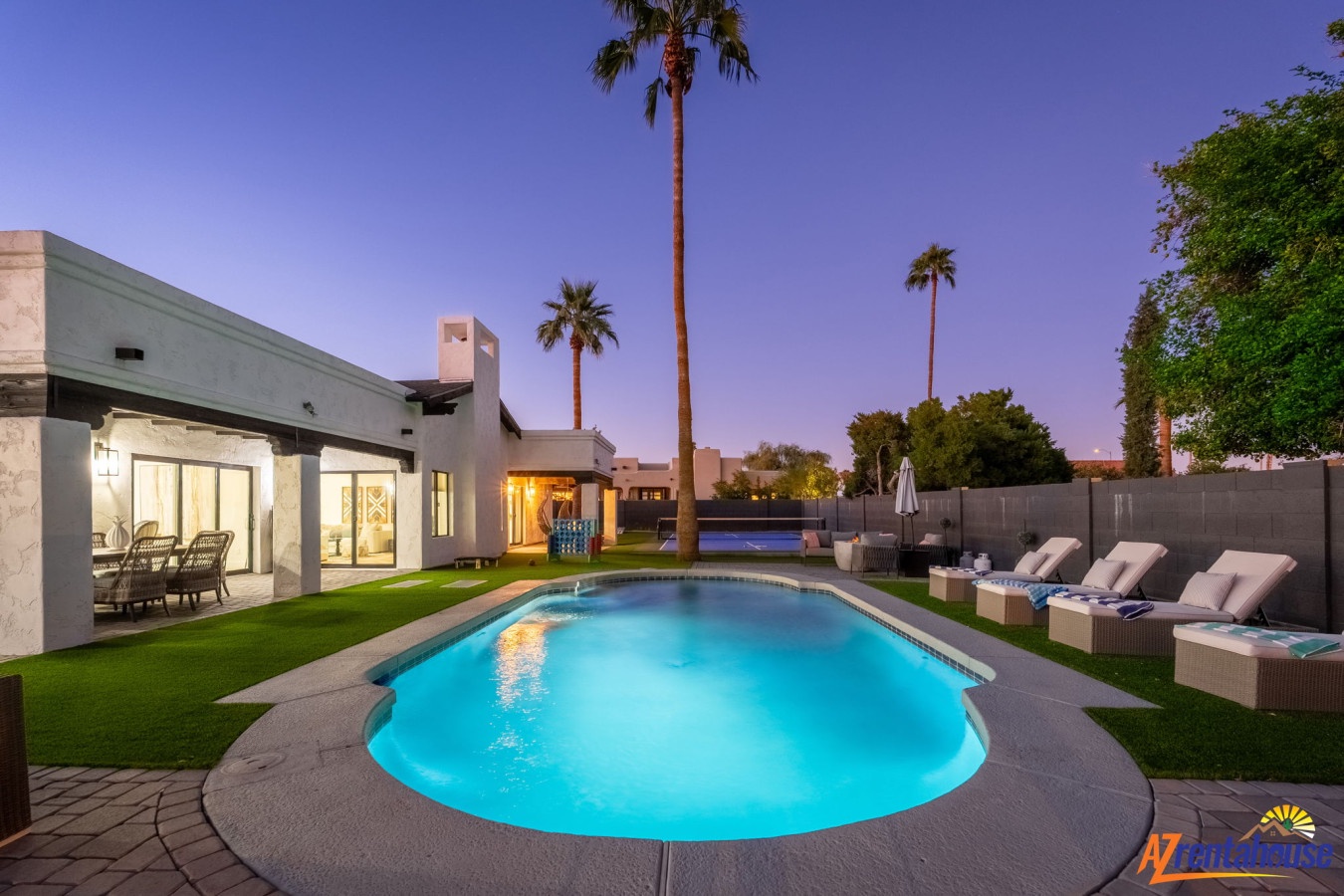 Modern desert oasis with sparkling pool surrounded by palm trees and luxury loungers at twilight.