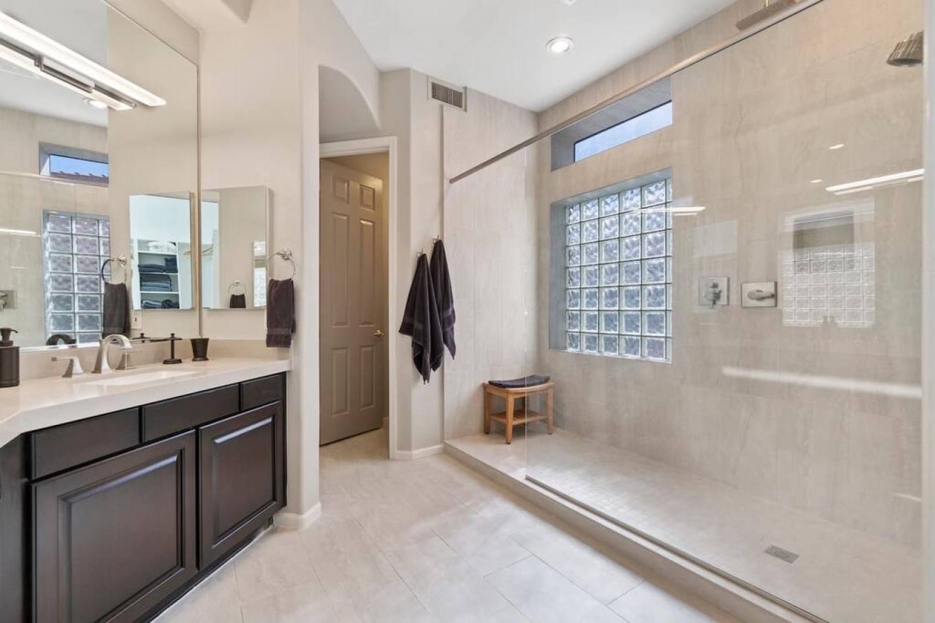Indulge in your private spa-like bathroom with a spacious walk-in shower and elegant glass block windows for natural light.