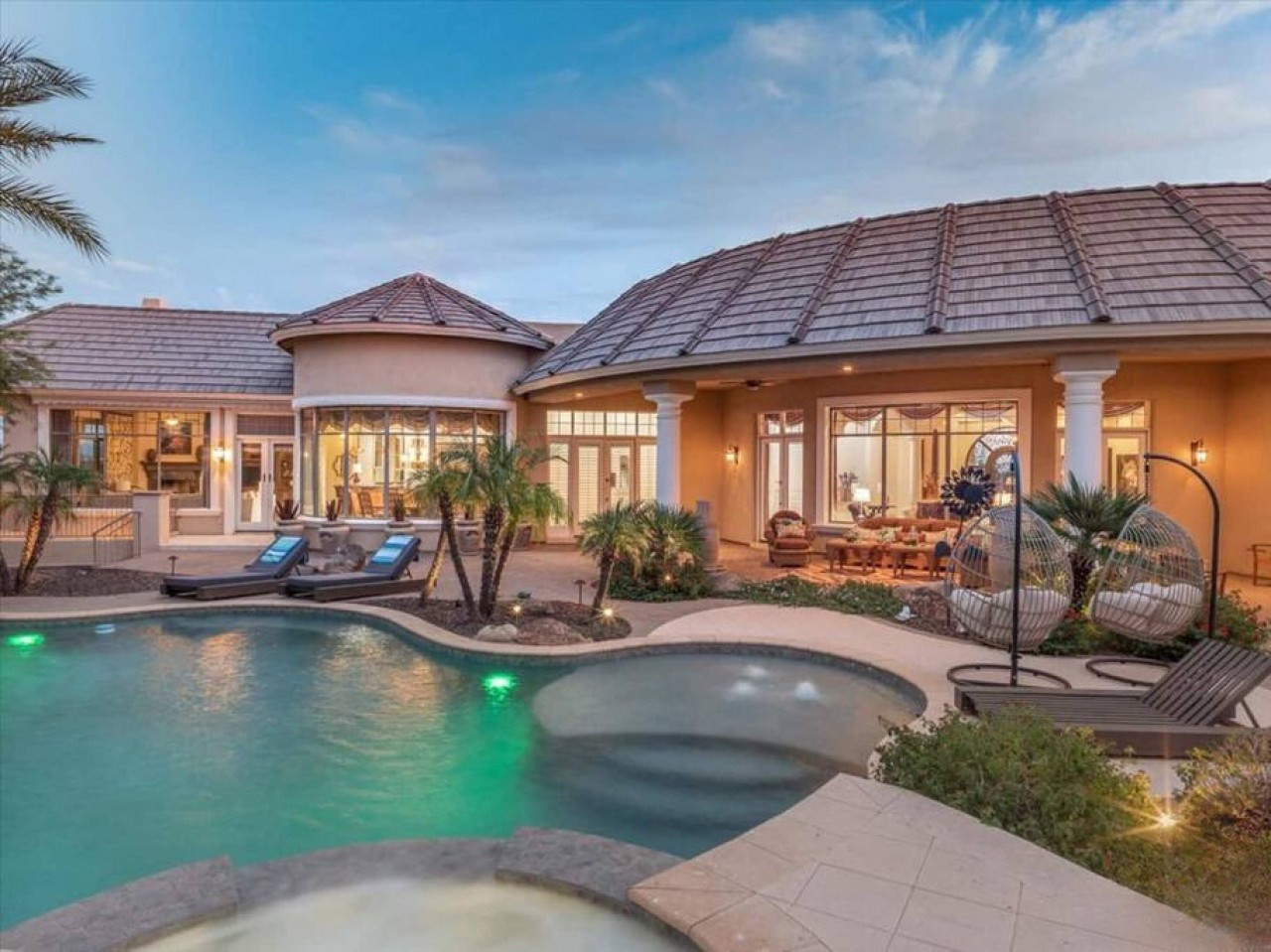 Picture yourself unwinding in this tropical paradise, where a stunning pool glows with ambient lighting and inviting lounge chairs await under swaying palms.