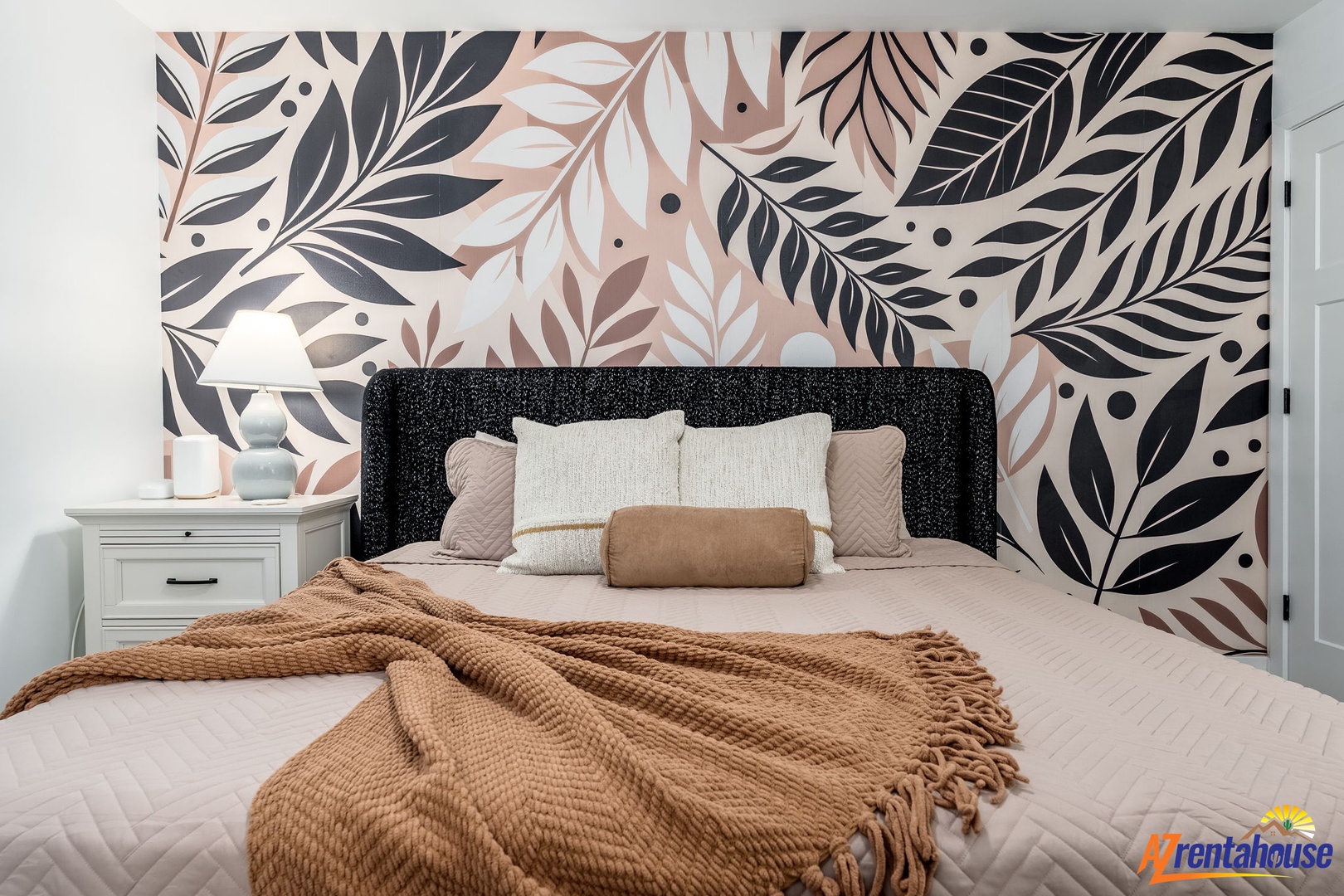 Drift off surrounded by botanical beauty in this stylish bedroom featuring a stunning accent wall and cozy earth-toned bedding.