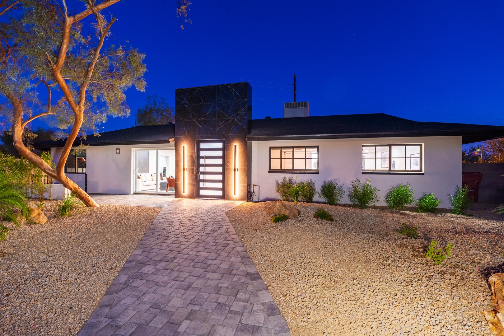Modern desert retreat with striking architectural lighting and landscaping creates an elegant arrival experience in a peaceful desert neighborhood.