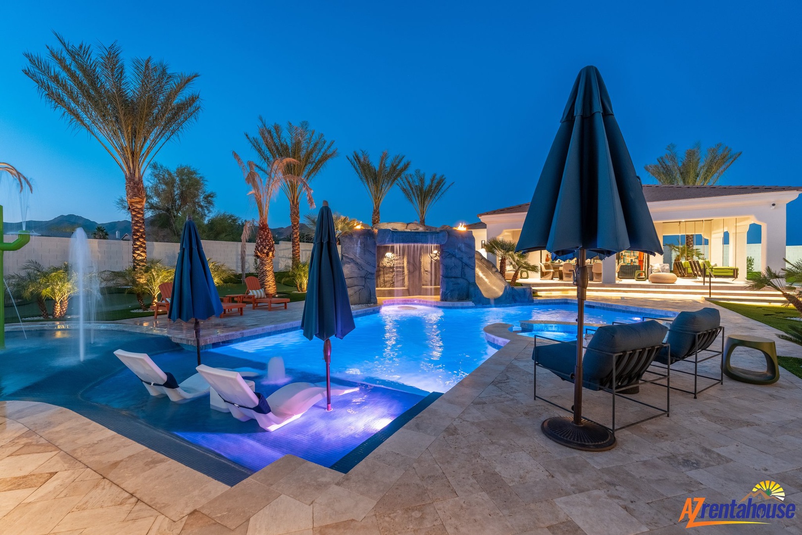 Stunning resort-style pool with illuminated water features and tropical palms creates the perfect evening retreat.