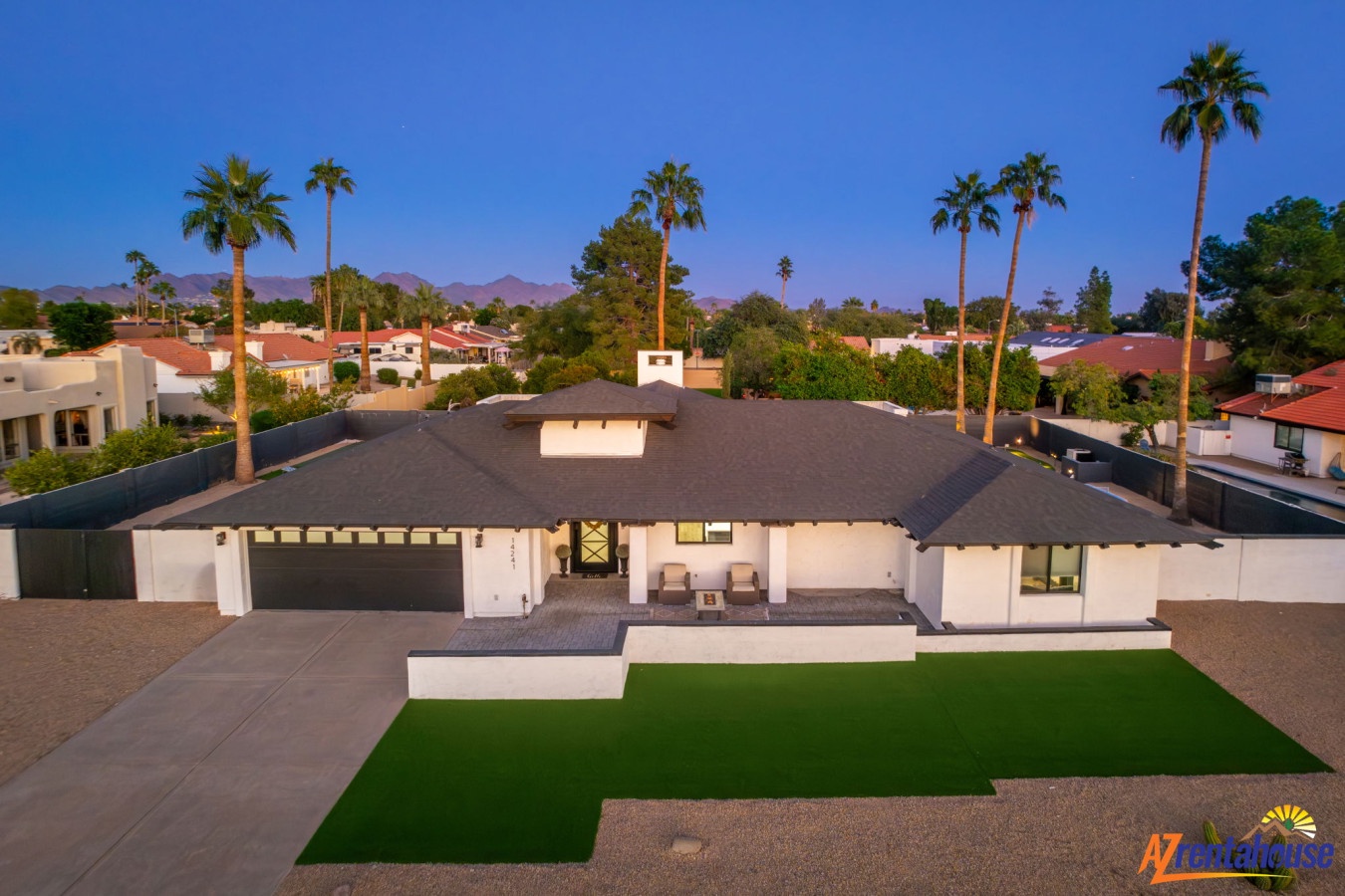 Modern desert retreat with mountain backdrop and palm-lined neighborhood setting.