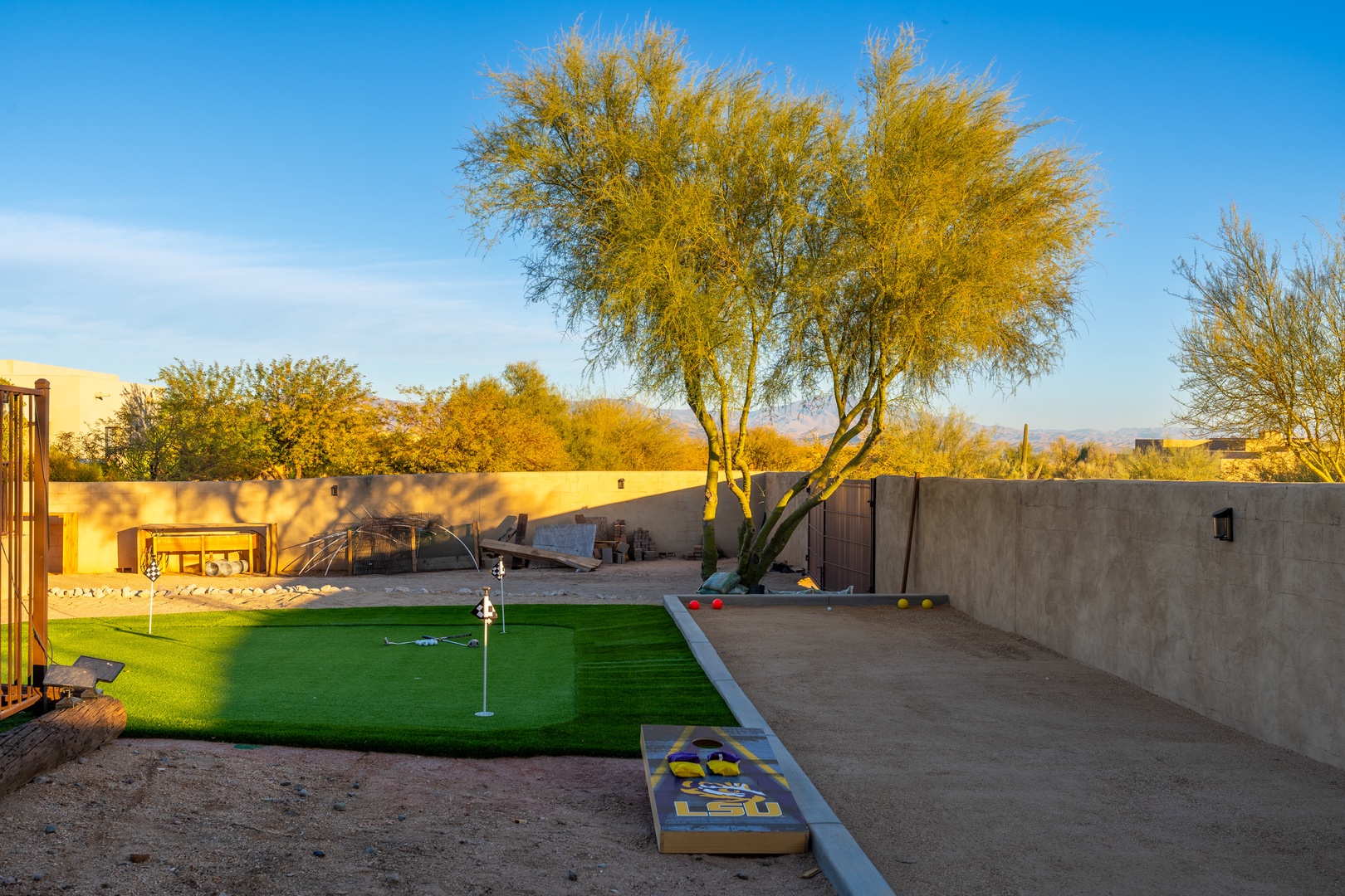 Private backyard retreat featuring a custom putting green, cornhole setup, and mature desert landscaping under wide open skies—perfect for outdoor fun and relaxation.