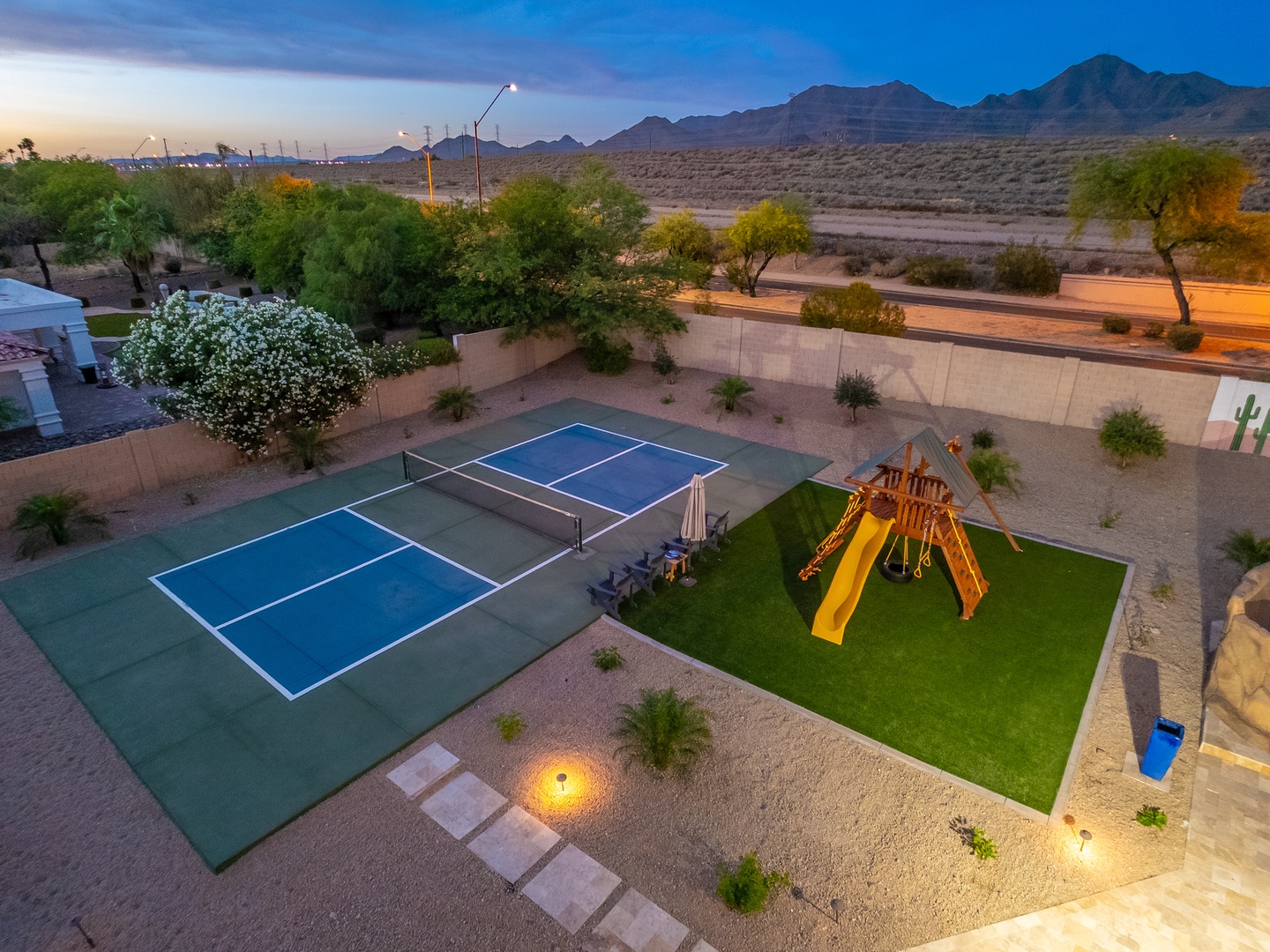 The property offers a private sports court, children's playground, and landscaped desert yard with mountain views beyond the neighborhood boundary.
