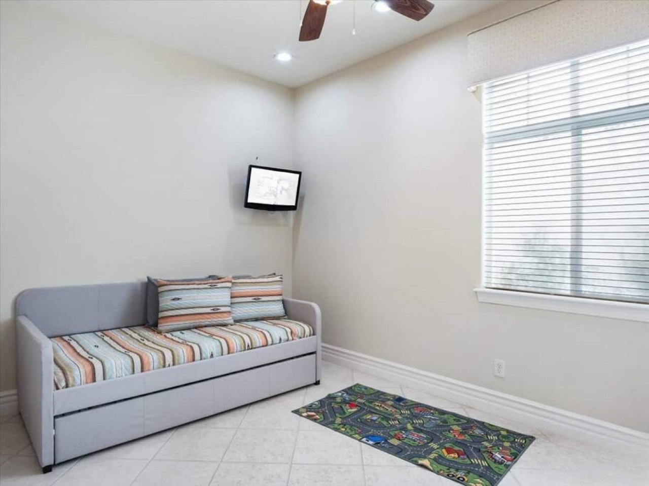 Relax in this bright, versatile space with a cozy daybed and wall-mounted TV. Perfect for unwinding after exploring or letting kids play on the fun rug.