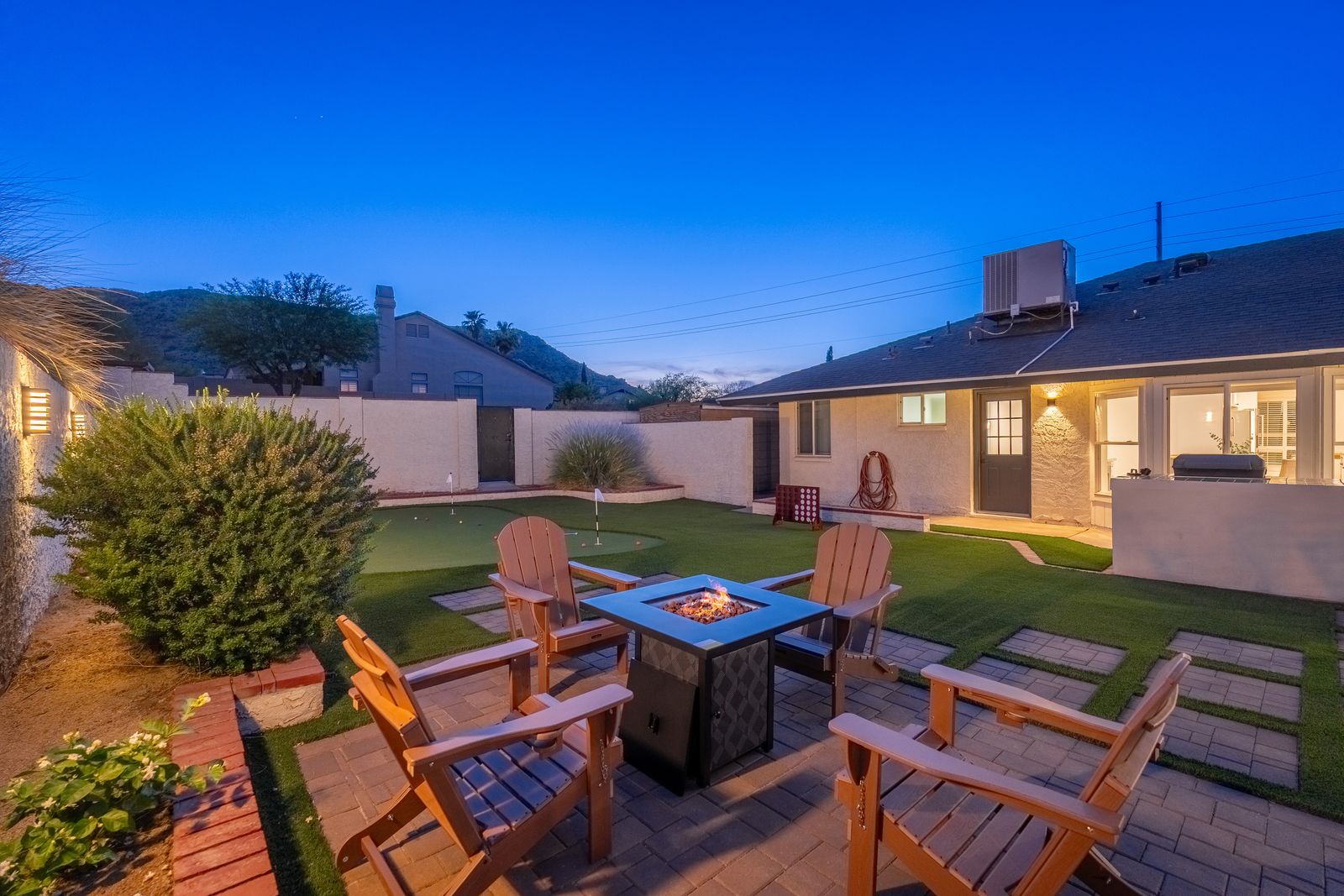 Gather around the cozy fire pit in your private backyard oasis, perfect for evening conversations under the stars. The landscaped yard features a putting green and connects to your spacious retreat.
