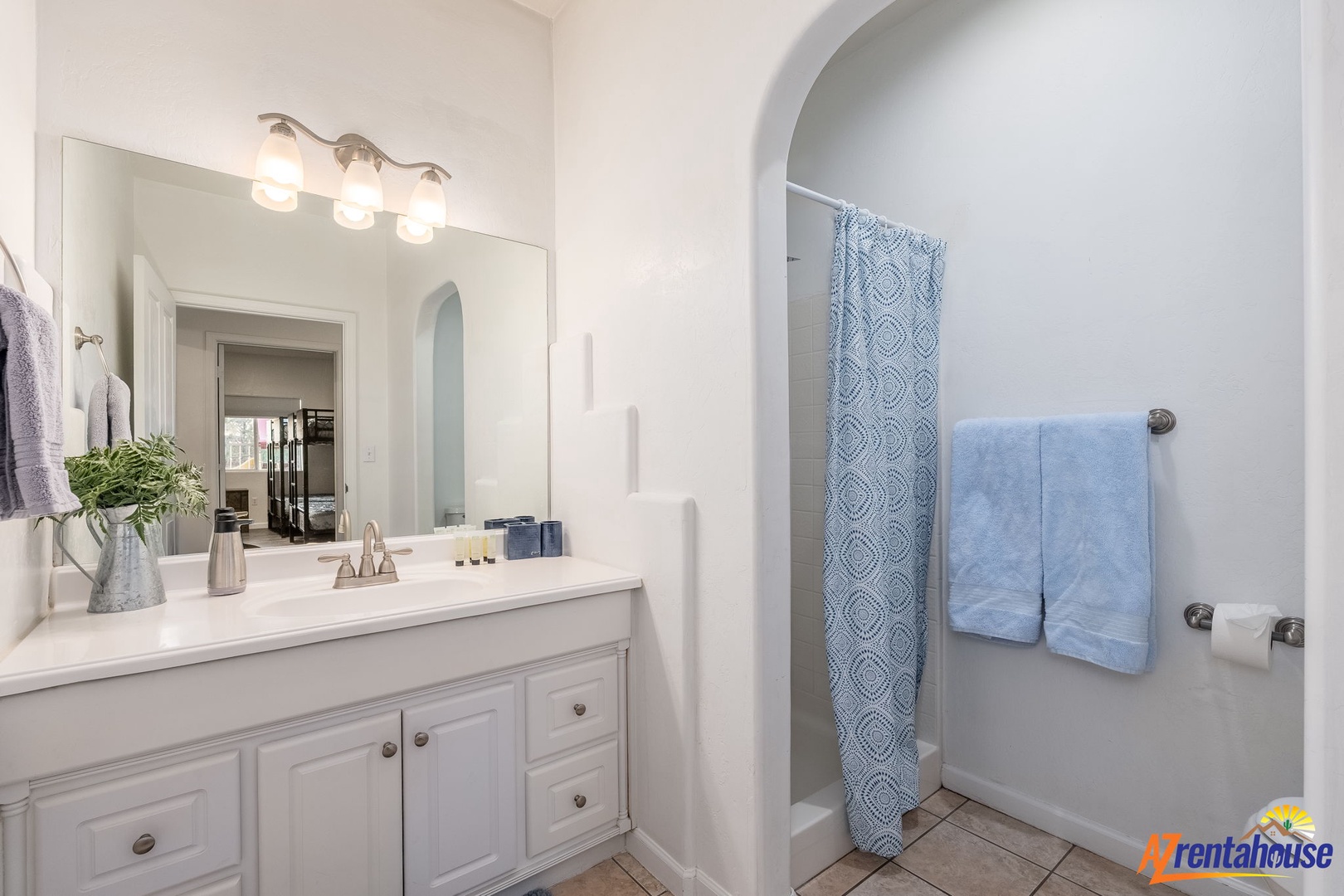 Freshen up in your bright, pristine bathroom with calming blue accents and an arched shower nook—your personal spa awaits after a day of adventure.