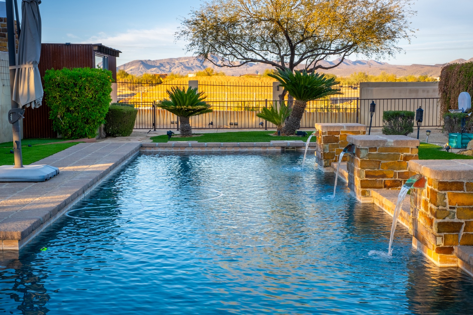 Sparkling pool with gentle water features and mountain vistas—your private desert oasis awaits under sunny skies.
