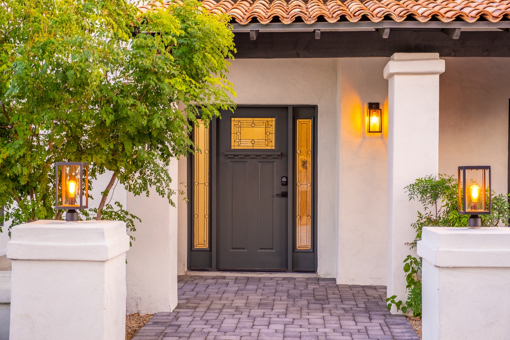 The property entrance features a welcoming façade with Mediterranean-style terracotta tile roof, ambient lighting, and mature landscaping providing a charming first impression for arriving guests.