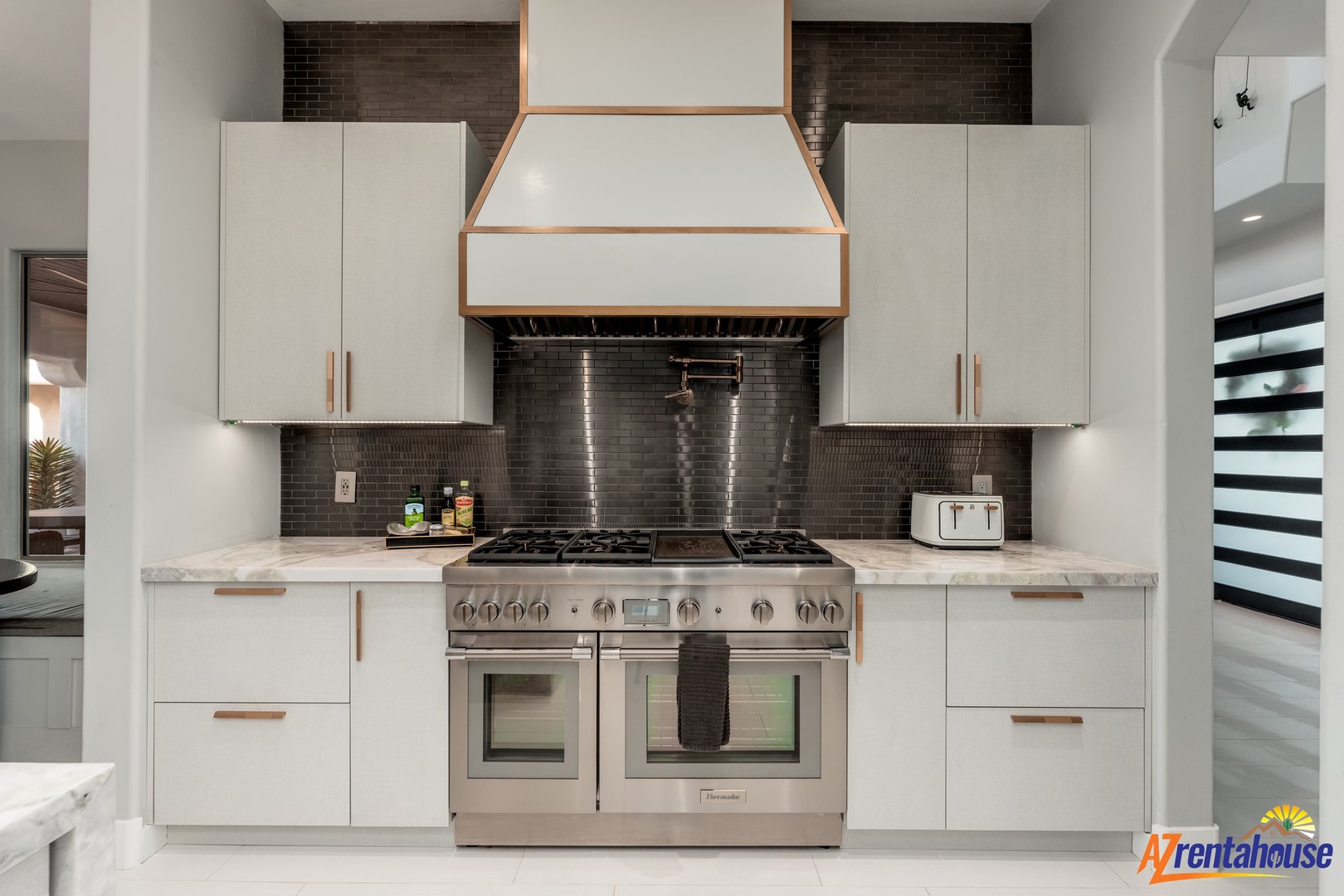 Your modern kitchen features professional-grade appliances, sleek white cabinetry, and striking dark tile backsplash for memorable culinary experiences.