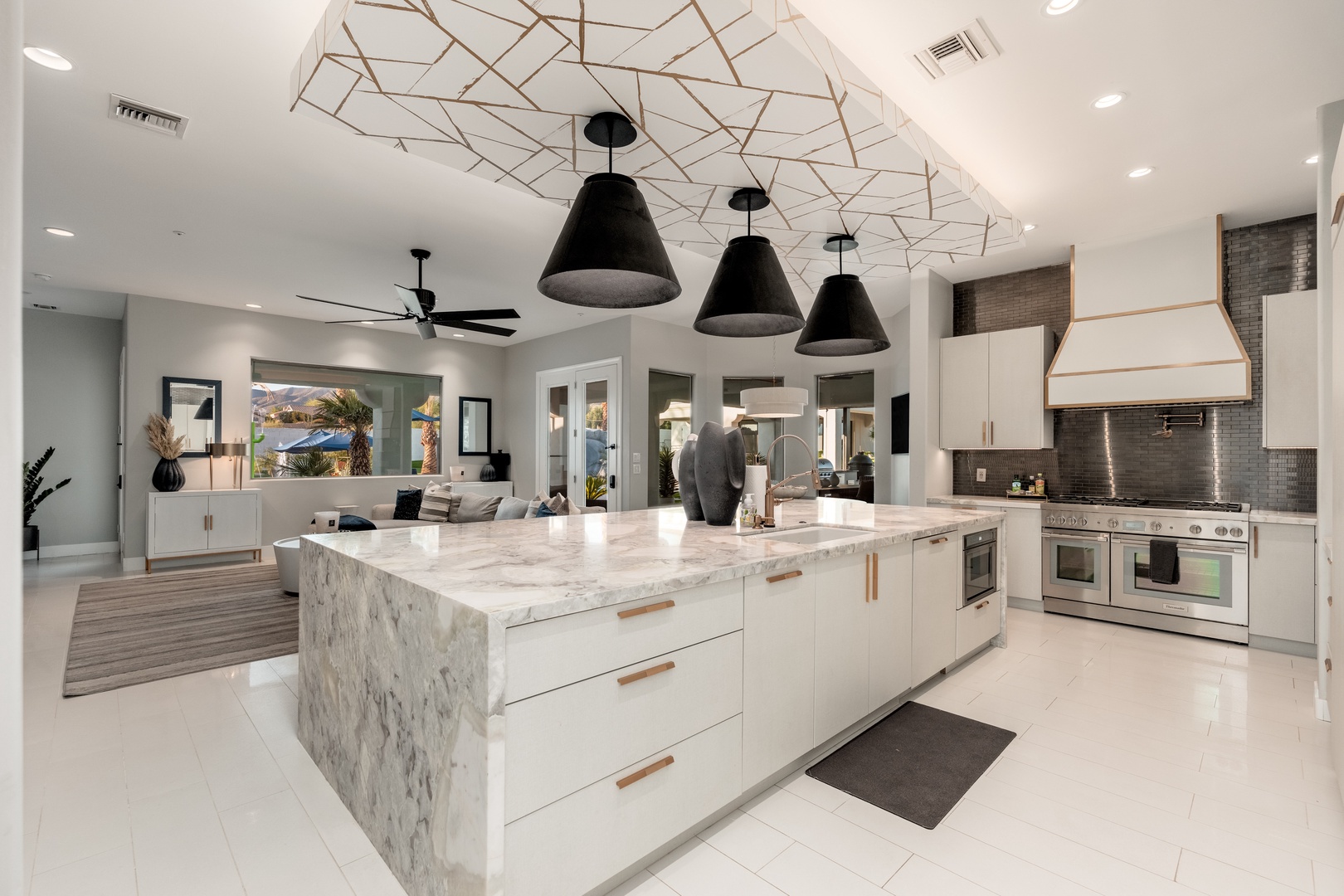Stunning modern kitchen with marble island, chef-grade appliances, and striking geometric ceiling detail—your culinary dreams come alive in this bright, open space.
