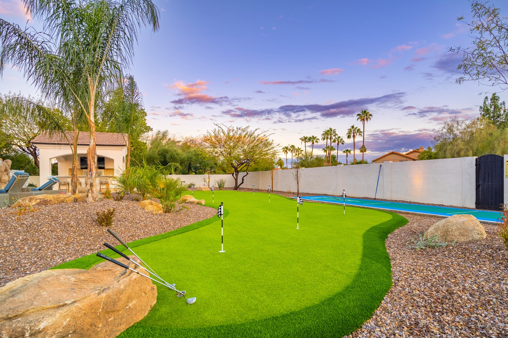 A desert oasis featuring a private putting green, sparkling pool, and lush palm trees beneath a stunning sunset sky—an ideal retreat for relaxation and recreation.