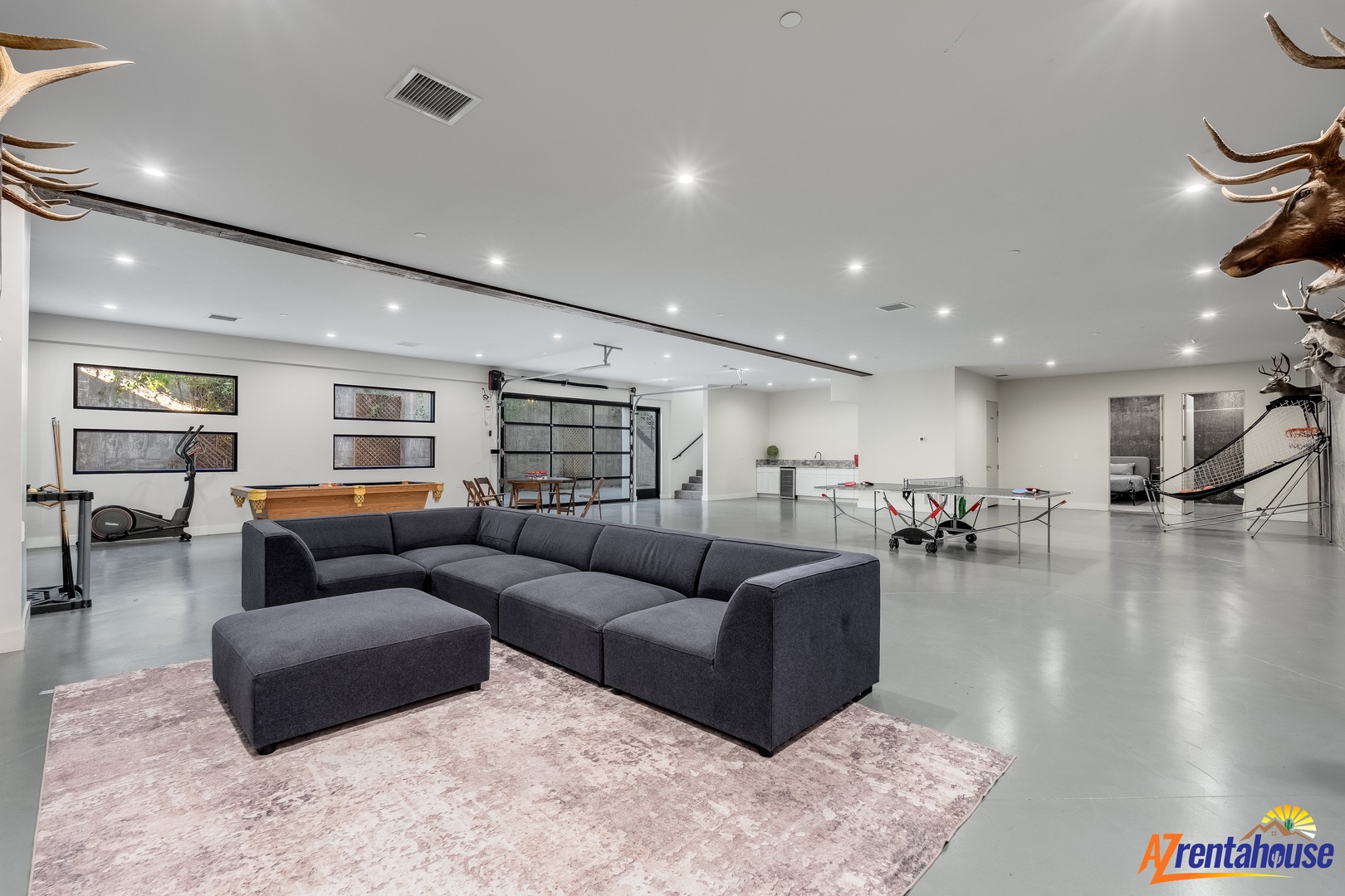 Step into your expansive modern game room featuring plush sectional seating, pool table, and unique rustic decor for ultimate relaxation.