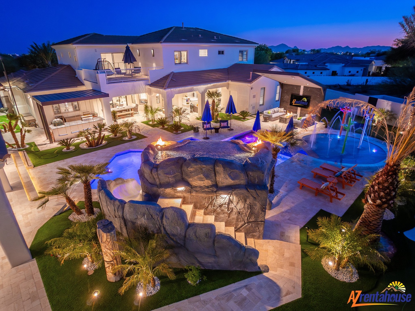 Stunning luxury villa with dramatic rock waterslide and blue-lit pool features, creating an unforgettable vacation paradise.