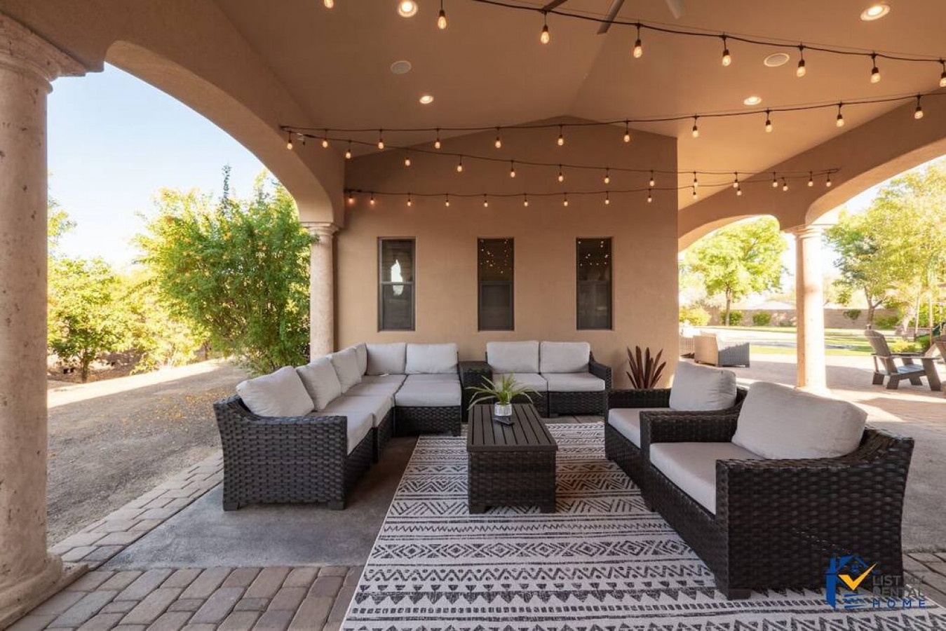 Unwind in your private covered patio with plush sectional seating and twinkling string lights creating perfect ambiance for evening relaxation.