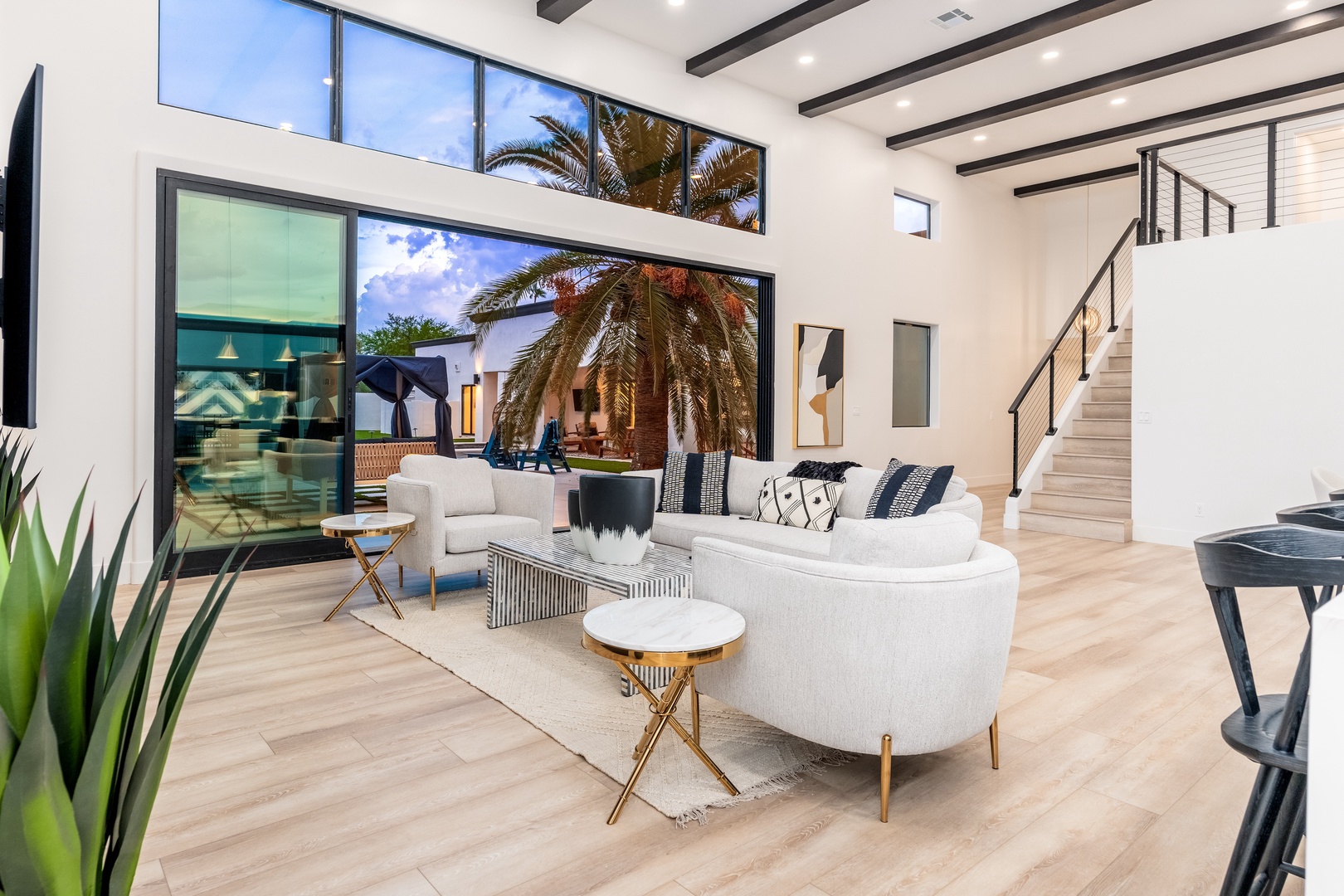 Sink into plush seating in this bright, airy living room where soaring ceilings and sunlight welcome you. Your private oasis awaits just beyond the glass doors, framed by swaying palms.