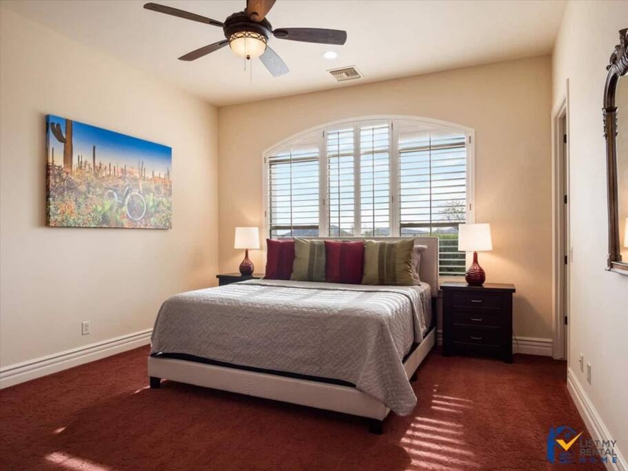 Your comfortable bedroom features desert-inspired decor, ceiling fan for cool nights, and beautiful arched windows with plantation shutters filtering warm sunlight.