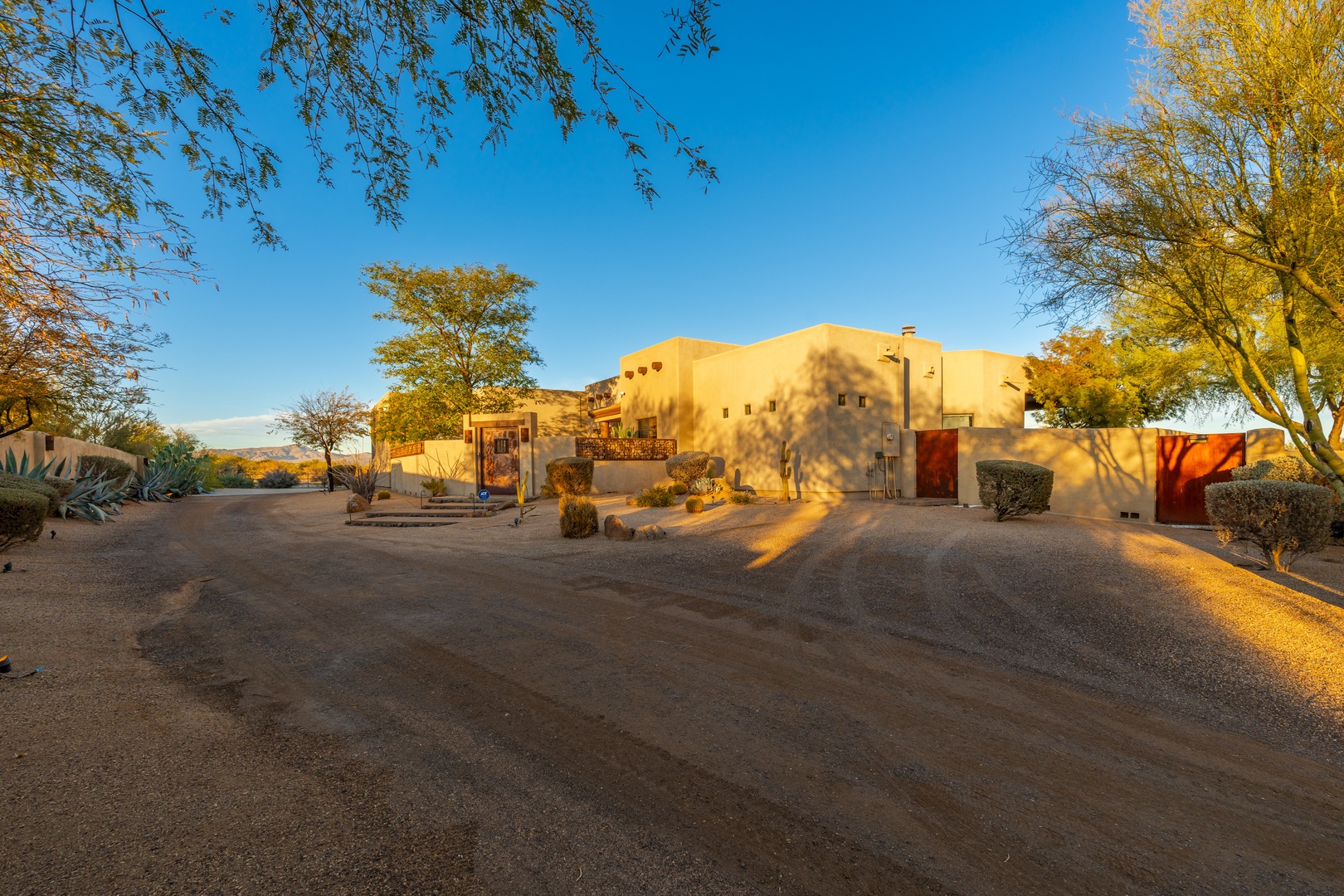 Adobe-style vacation rental set among desert landscapes, framed by golden autumn foliage and clear blue skies, offering a serene southwestern retreat.