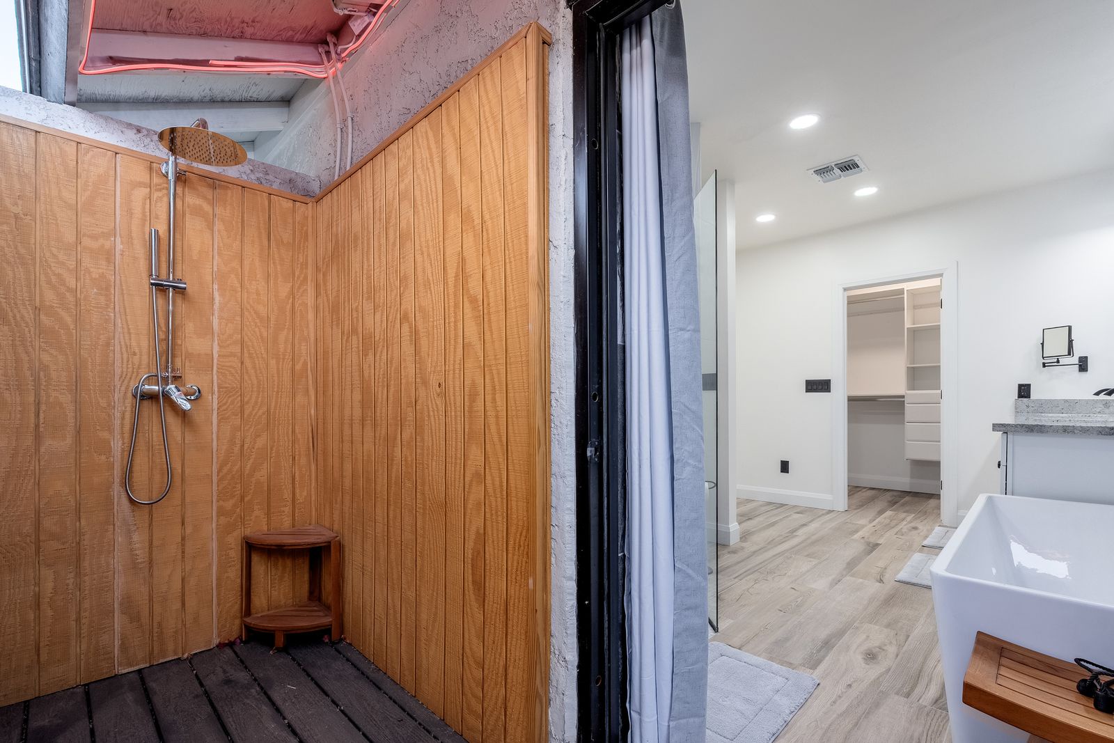 Rinse off under your private outdoor shower, surrounded by warm wood panels and open sky, then step inside to a bright, modern bathroom with everything you need.