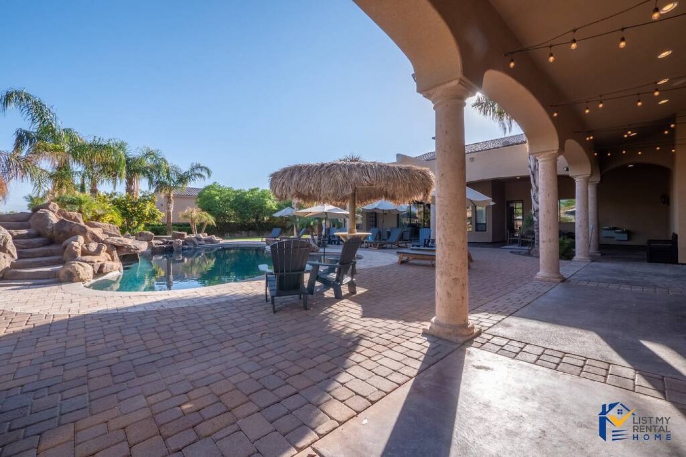 Step onto your private covered patio where elegant columns frame stunning pool views and tropical landscaping creates your perfect retreat.