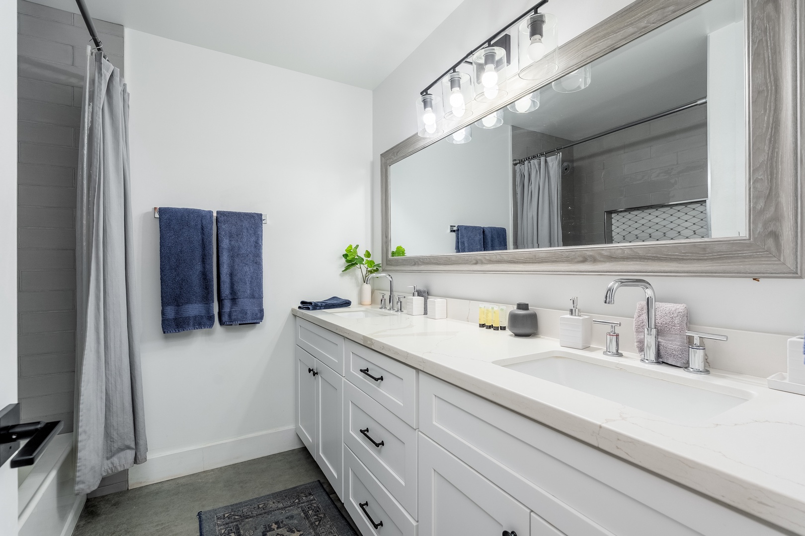 Your bright, modern bathroom features dual sinks with crisp white counters, soft towels, and gentle lighting—perfect for refreshing mornings before exploring.