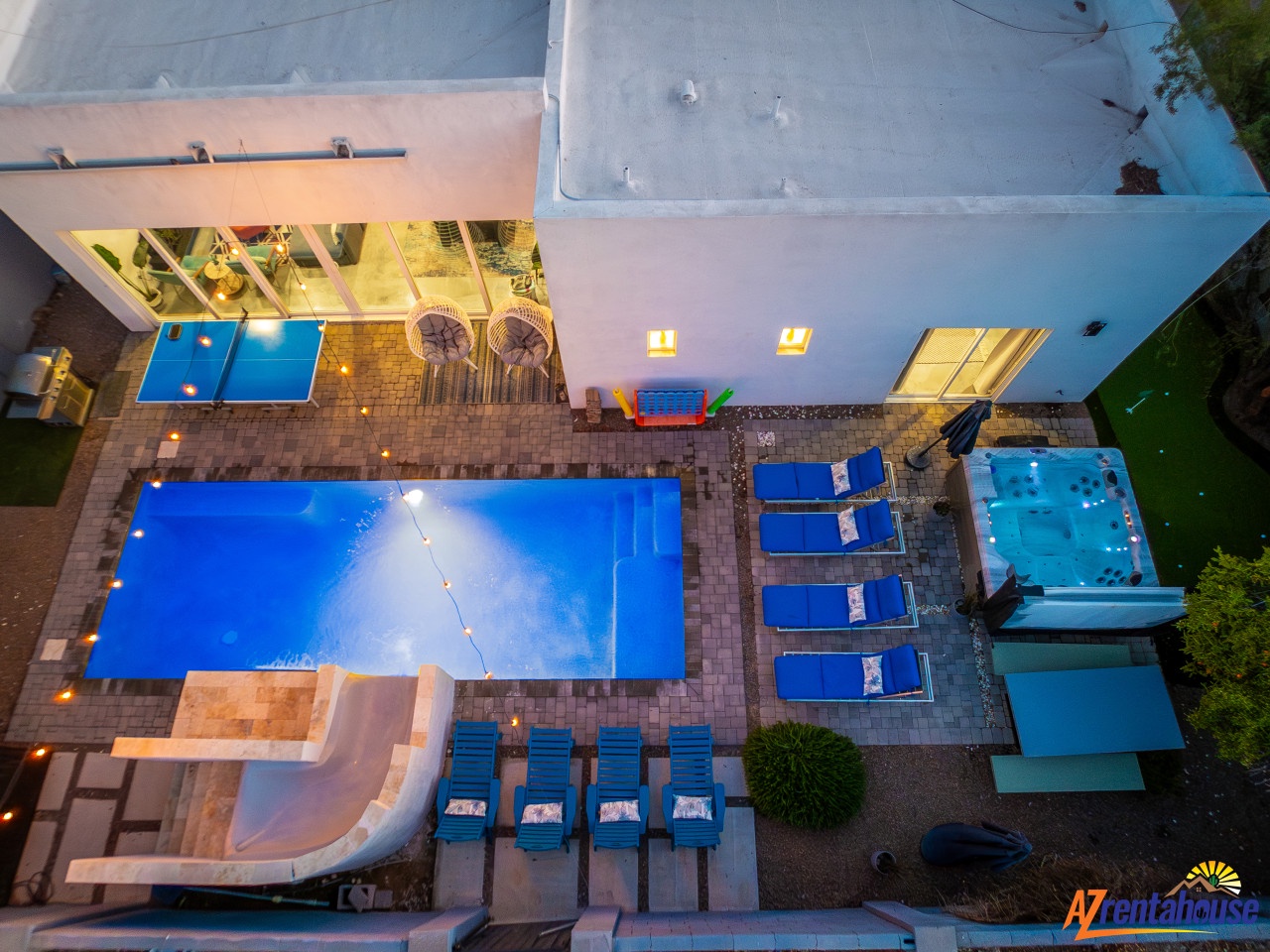 Aerial view of modern vacation rental featuring swimming pool, hot tub, and spacious patio with outdoor lounge seating.