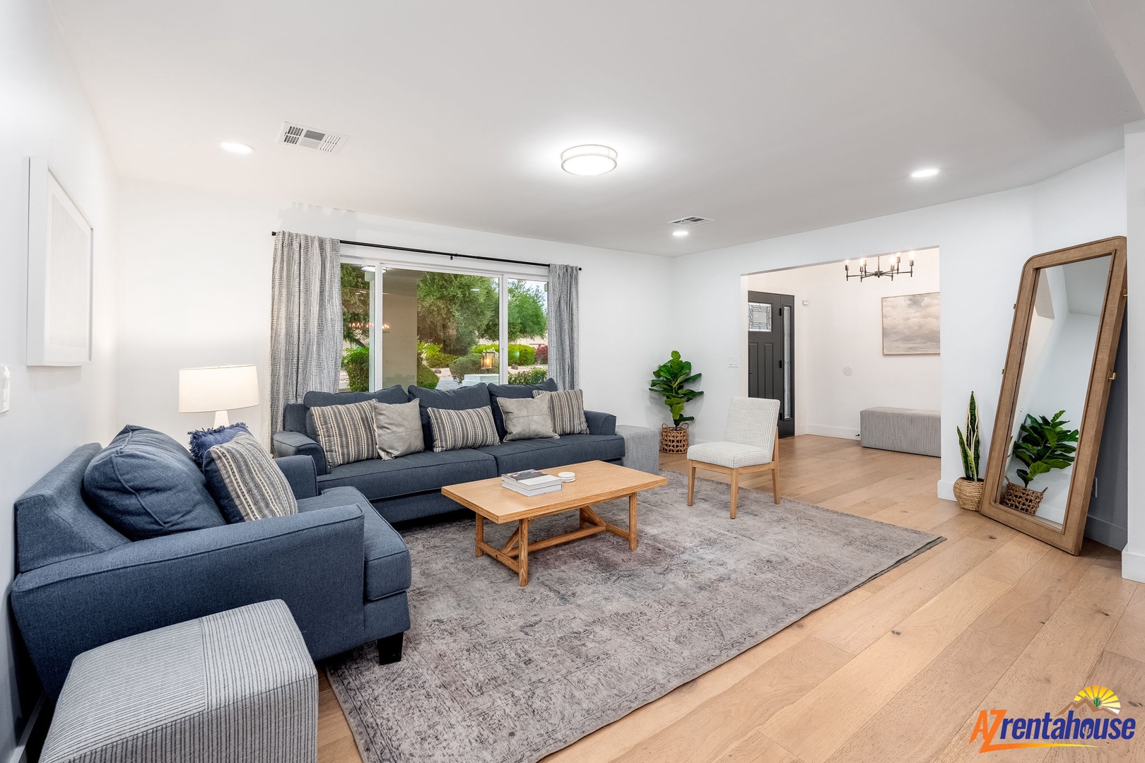 Sink into plush navy sofas in your bright, airy living room where natural light streams through sliding doors to your private patio garden.