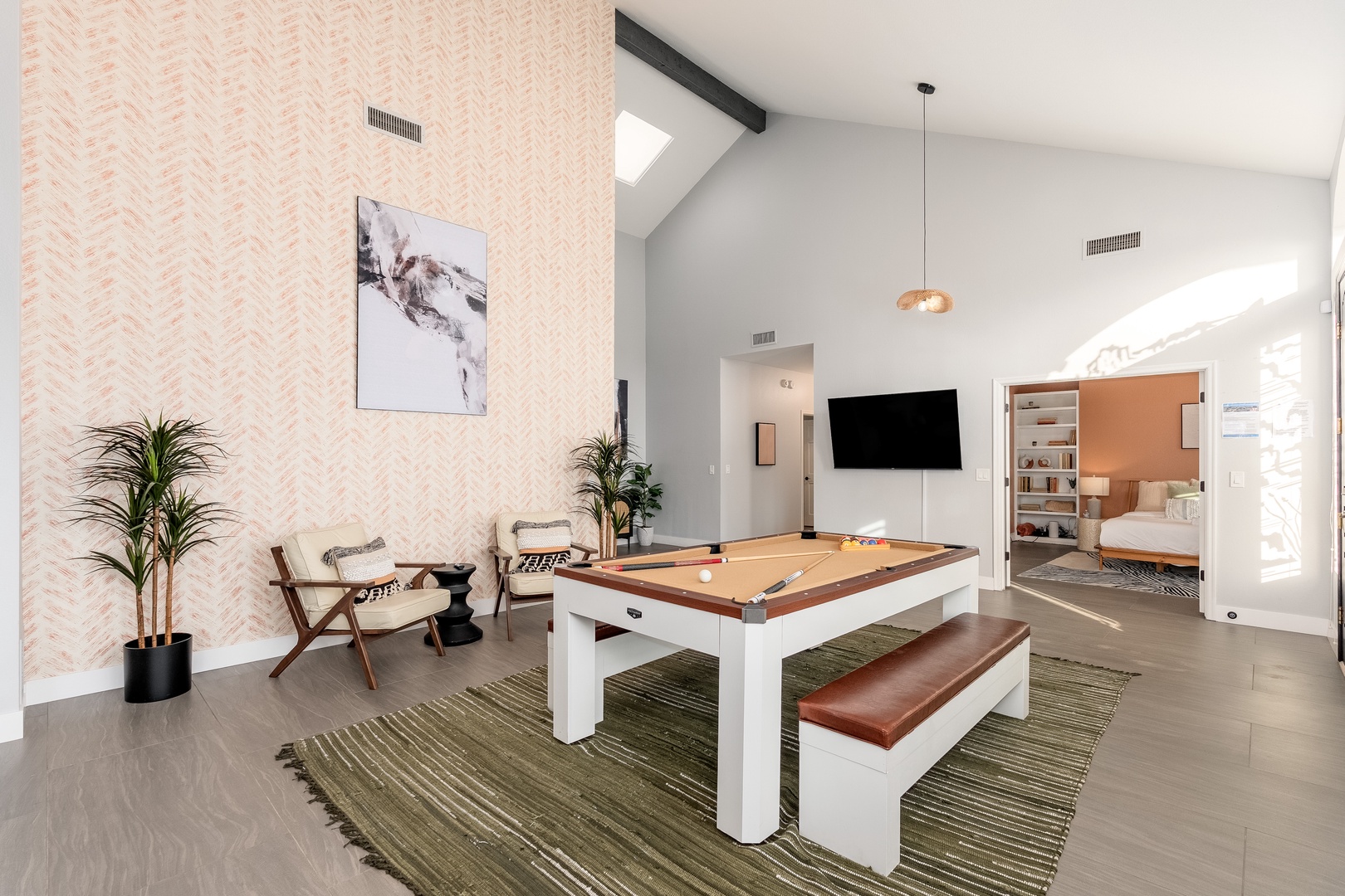 A stylish game room where you'll gather for friendly competition. High ceilings, modern accents, and a sleek billiards table create the perfect backdrop for memorable evenings with loved ones.