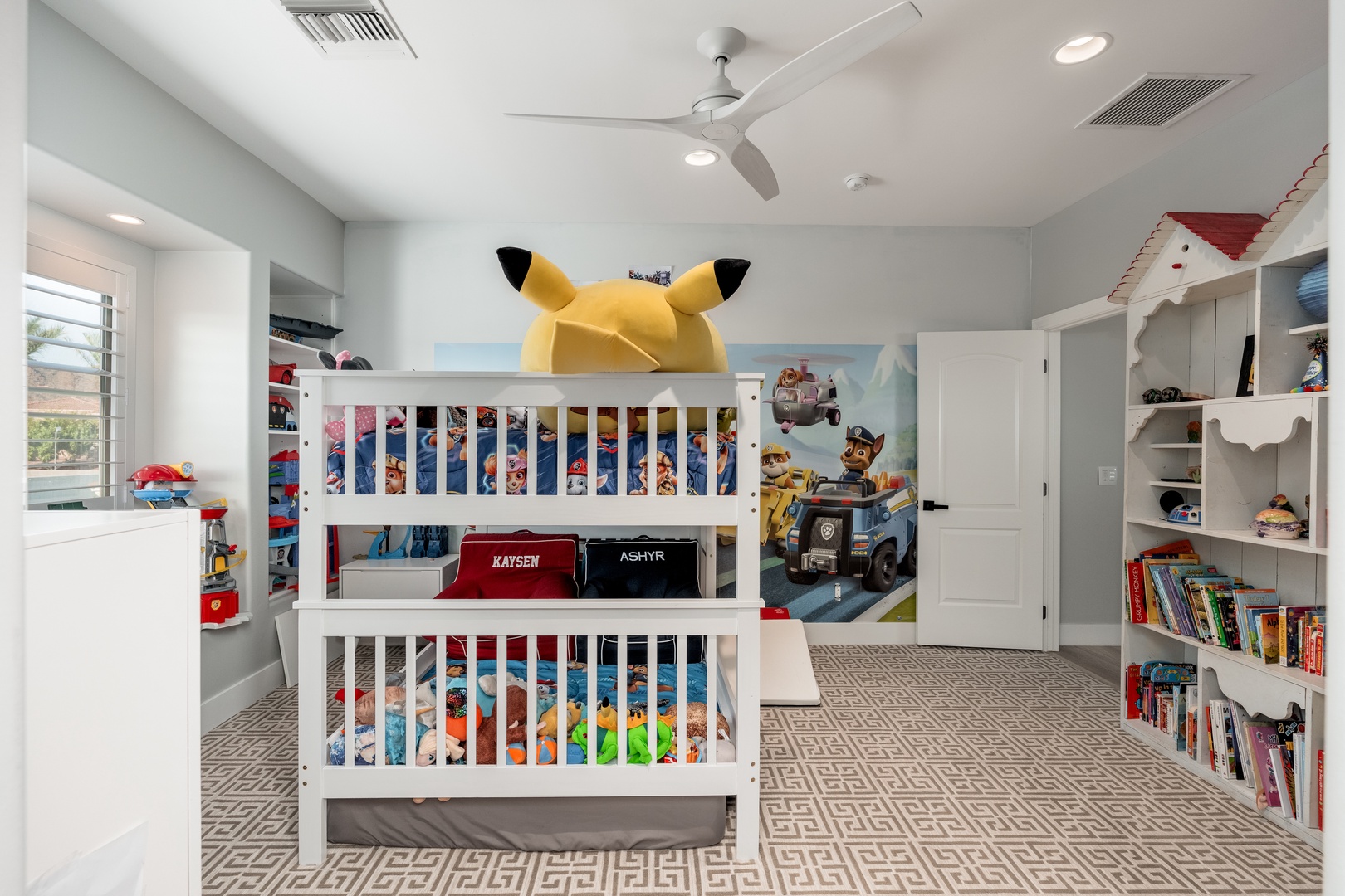 Playful kids' room featuring themed white bunk beds, colorful storage, a fun ceiling fan, and whimsical character artwork to spark imagination.