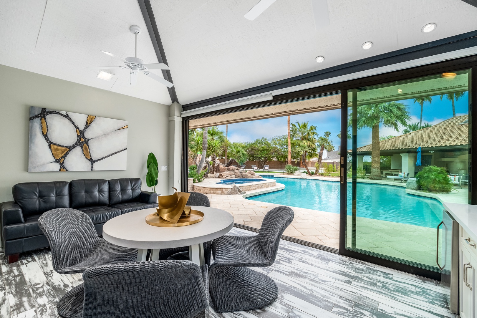 Sink into the plush seating and soak up stunning poolside views from this light-filled living space, where modern comfort meets tropical paradise just beyond your private patio doors.