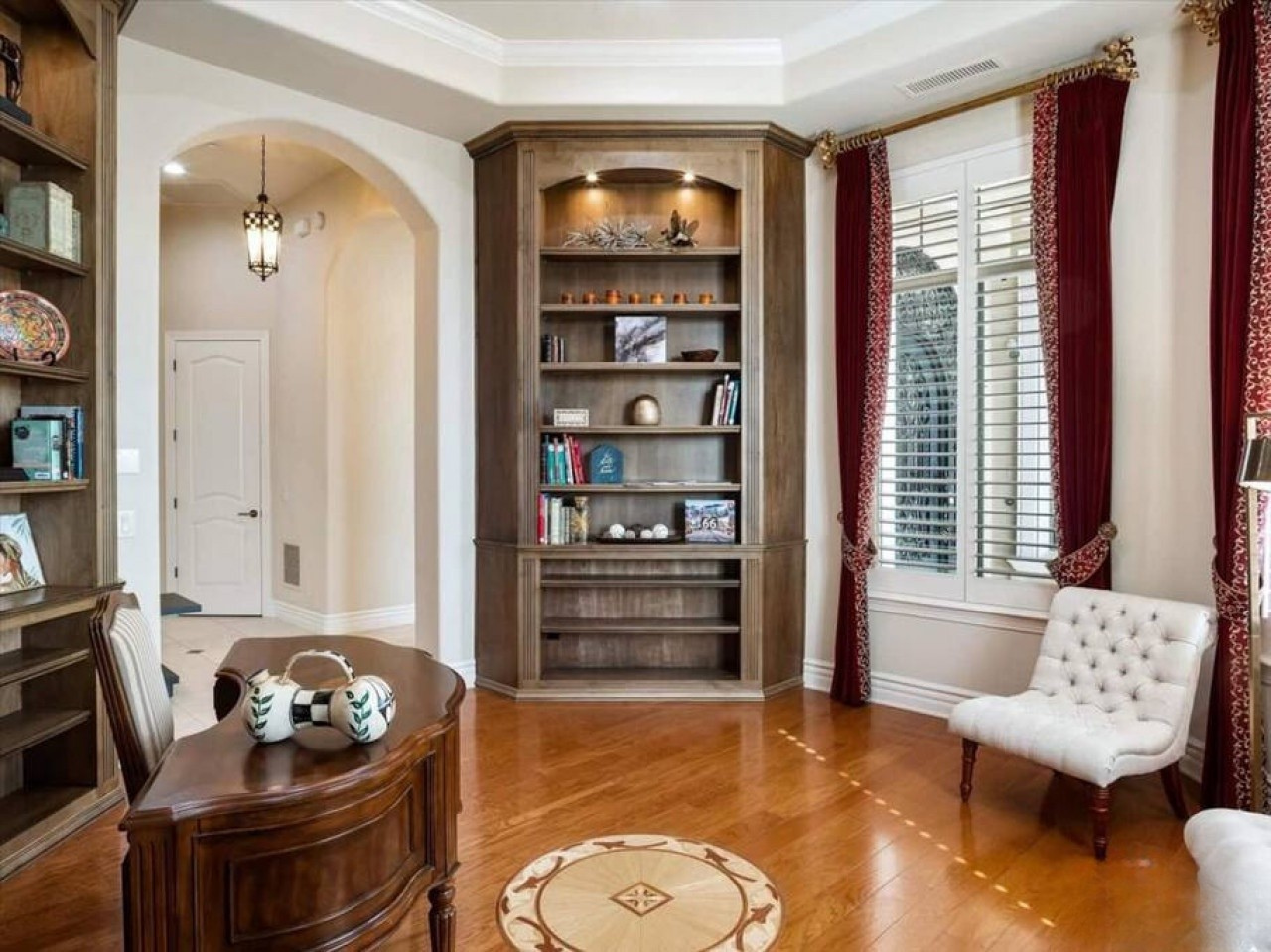 Settle into your elegant study, where rich wood tones, beautiful built-ins, and warm sunlight create an inviting space for reading, working, or simply unwinding in comfort.