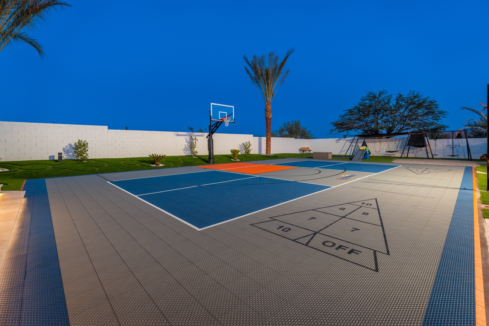 Full-sized sport court with basketball hoop, shuffleboard markings, and playground—perfect for family fun under clear desert skies.
