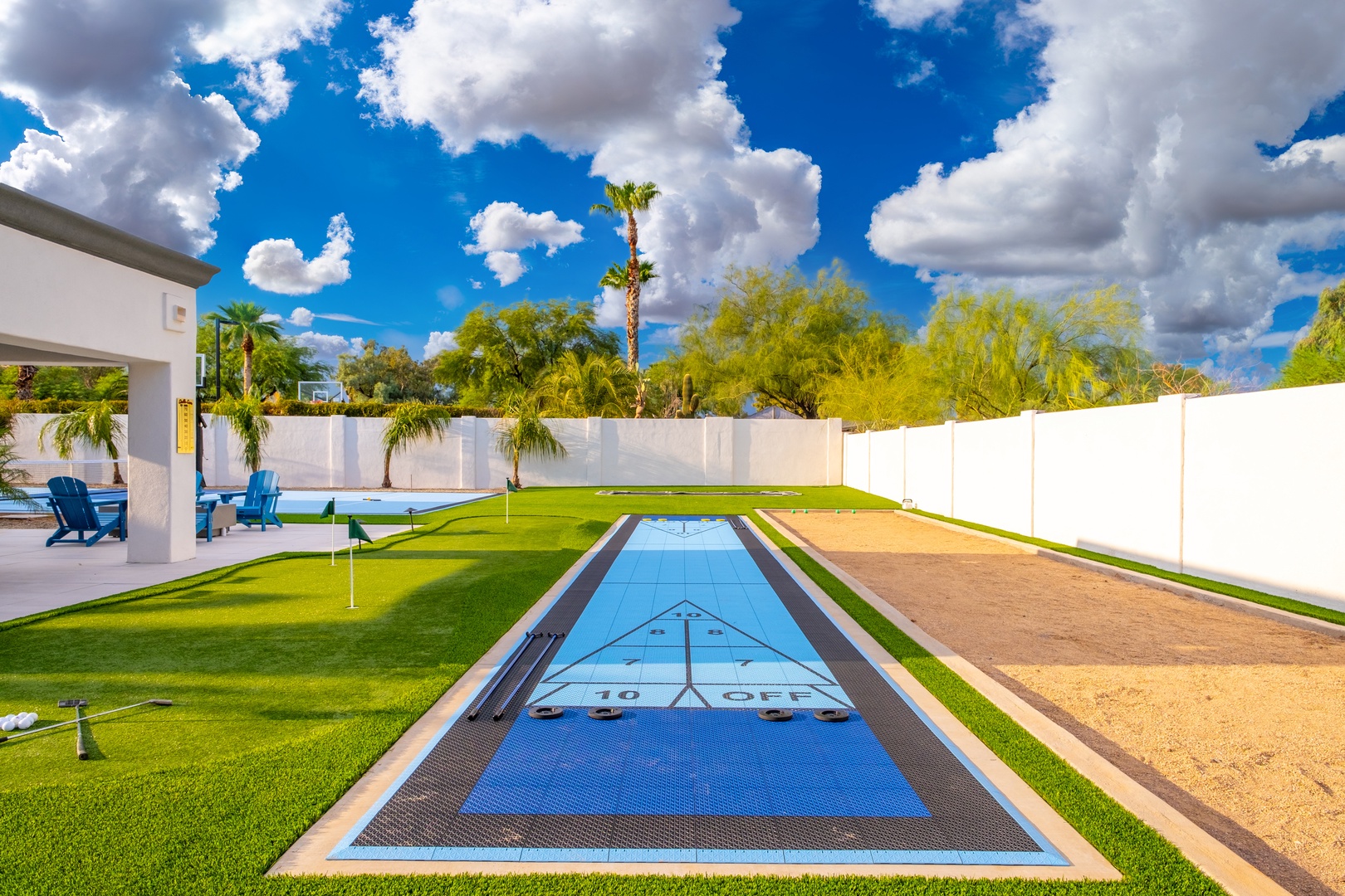 A stunning outdoor retreat featuring a private shuffleboard court, lush green lawn, vibrant palm trees, and a sparkling blue sky overhead—perfect for friendly competition and relaxation.