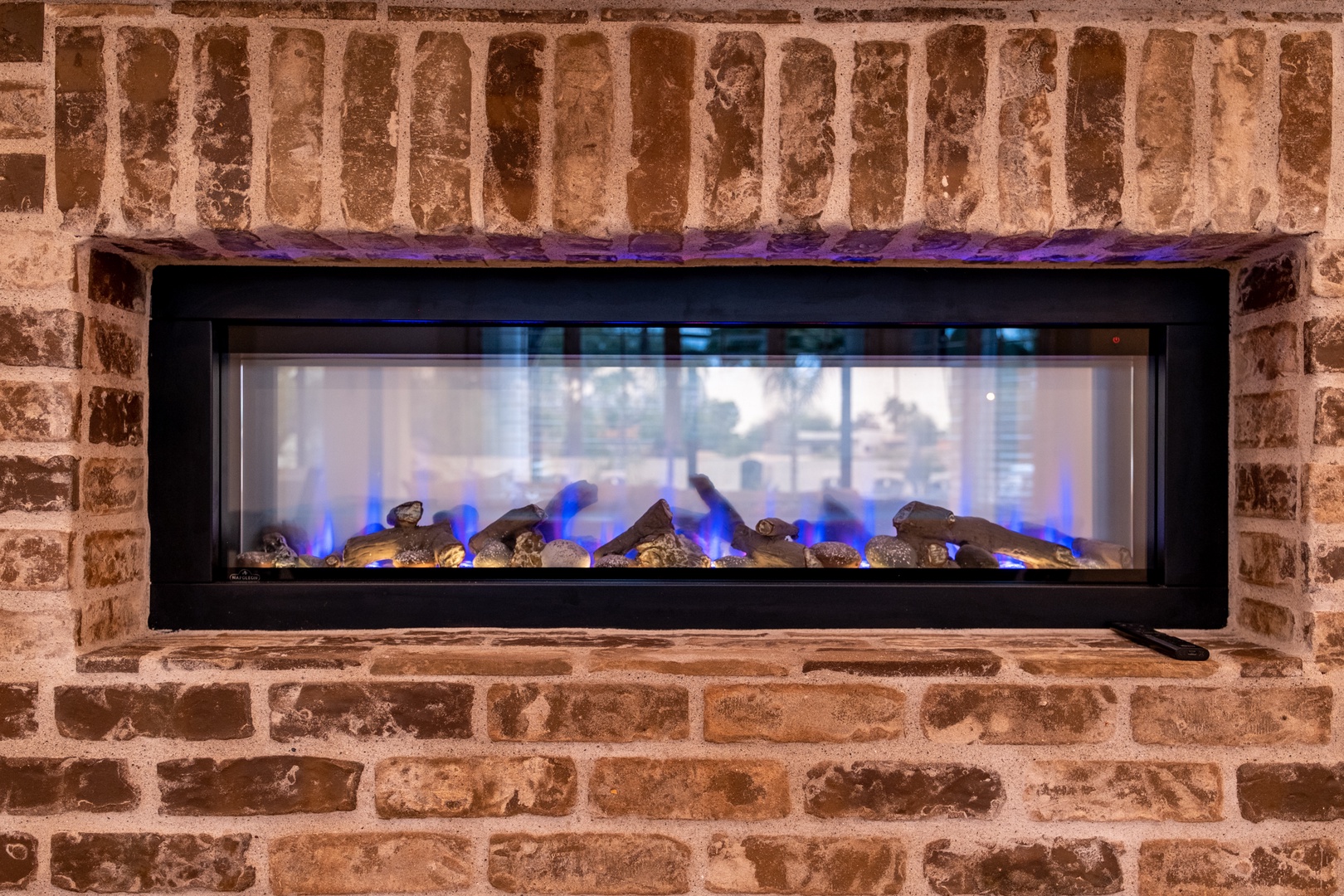 Gather around the beautiful fireplace with its modern blue flames dancing against rustic exposed brick—perfect for cozy evenings in your home away from home.