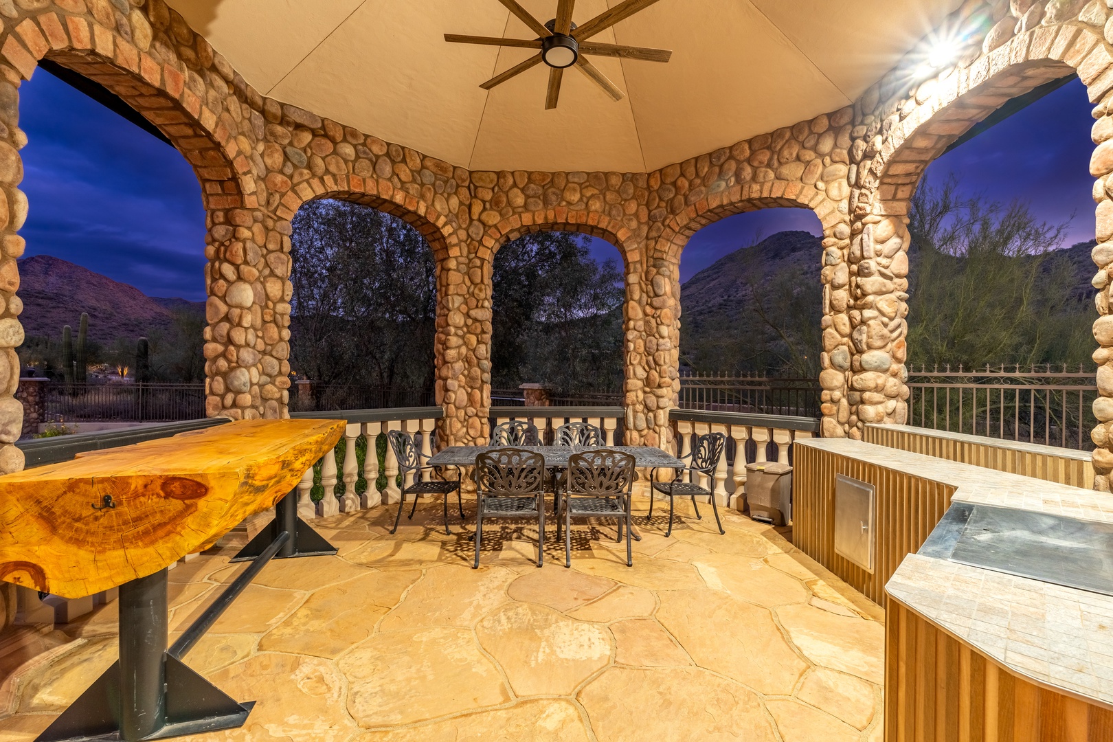 Unwind in your private covered patio with elegant stone archways framing mountain views. Soak in the hot tub under the stars or gather at the table for evening conversations in this peaceful retreat.