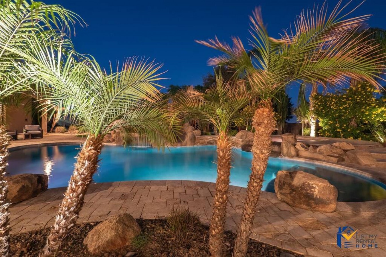 Tropical pool paradise awaits with illuminated palm trees and glowing blue waters for your evening relaxation.