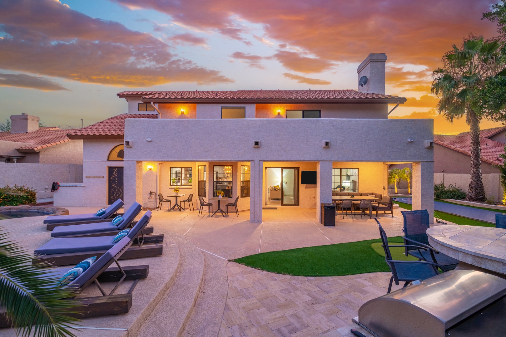 A stunning Spanish-style vacation home with terracotta tile roof and arched architectural details, featuring spacious outdoor living areas perfect for entertaining at sunset.