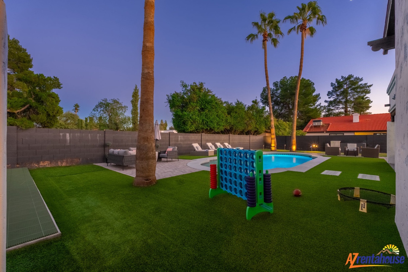 Your private backyard oasis features a sparkling pool, outdoor games, and palm trees under twilight skies—perfect for family fun and relaxation.