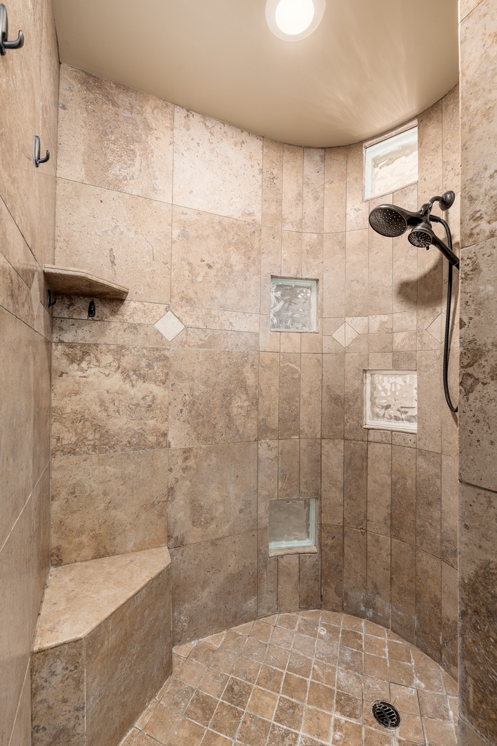 Step into your private shower retreat with elegant travertine tile, dual showerheads, built-in bench, and niche storage for your essentials. Your peaceful morning routine awaits.