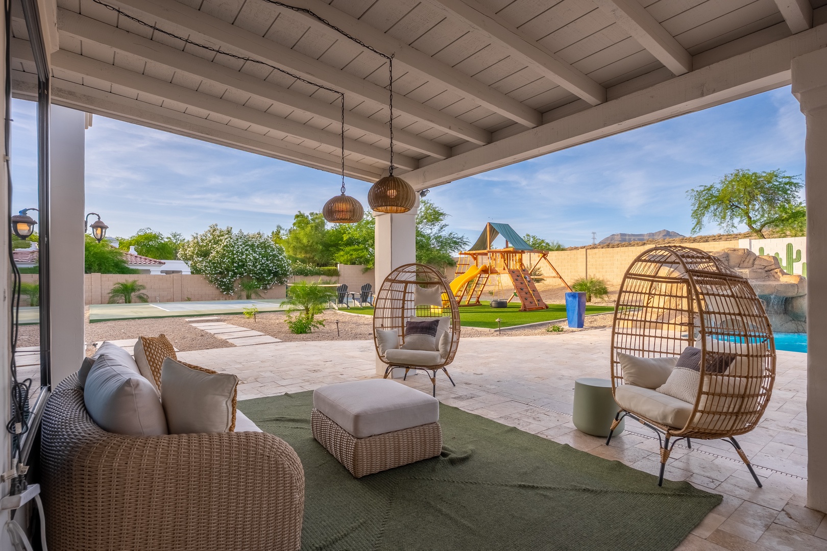 Unwind in your private covered patio with cozy seating, where mountain views meet desert tranquility and a sparkling pool beckons just beyond the lounge.
