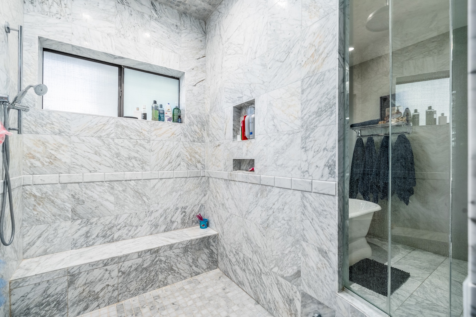 Luxurious marble-clad bathroom with built-in tub and sleek glass shower, designed for your ultimate relaxation and comfort.