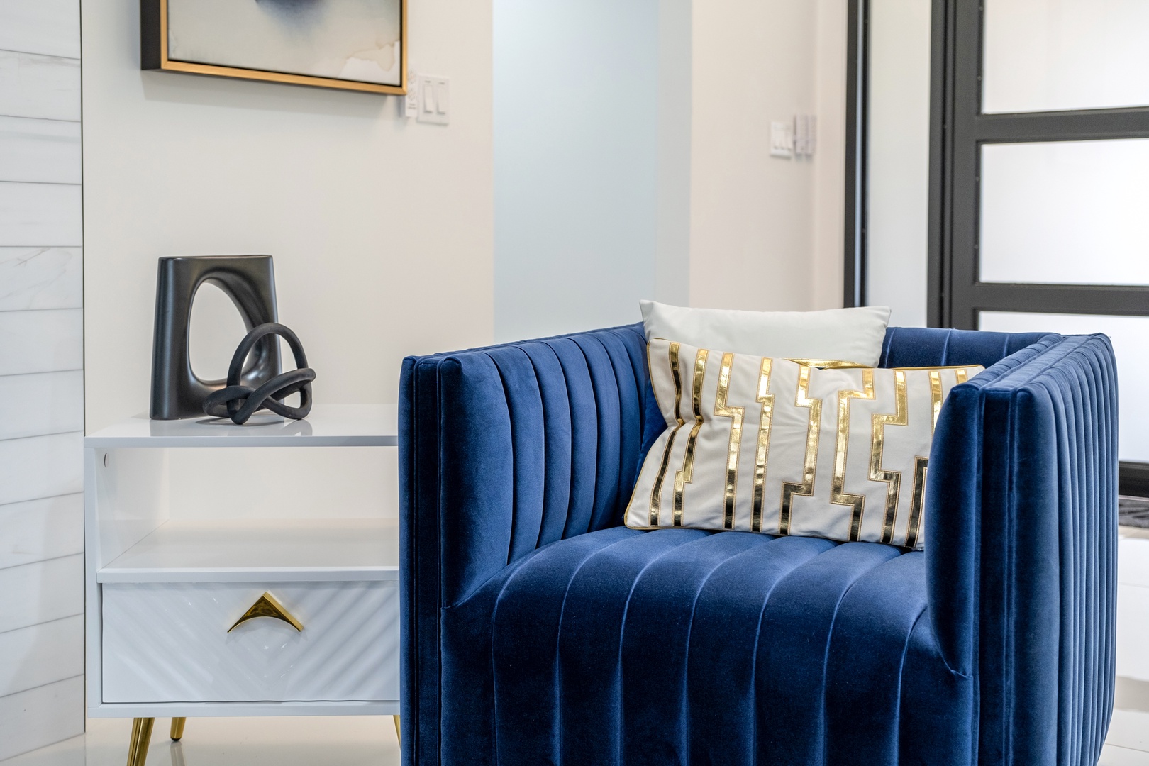 Sink into plush velvet comfort in your stylish living space. The rich blue tones and gleaming gold accents create an inviting spot where you can unwind after exploring all day.