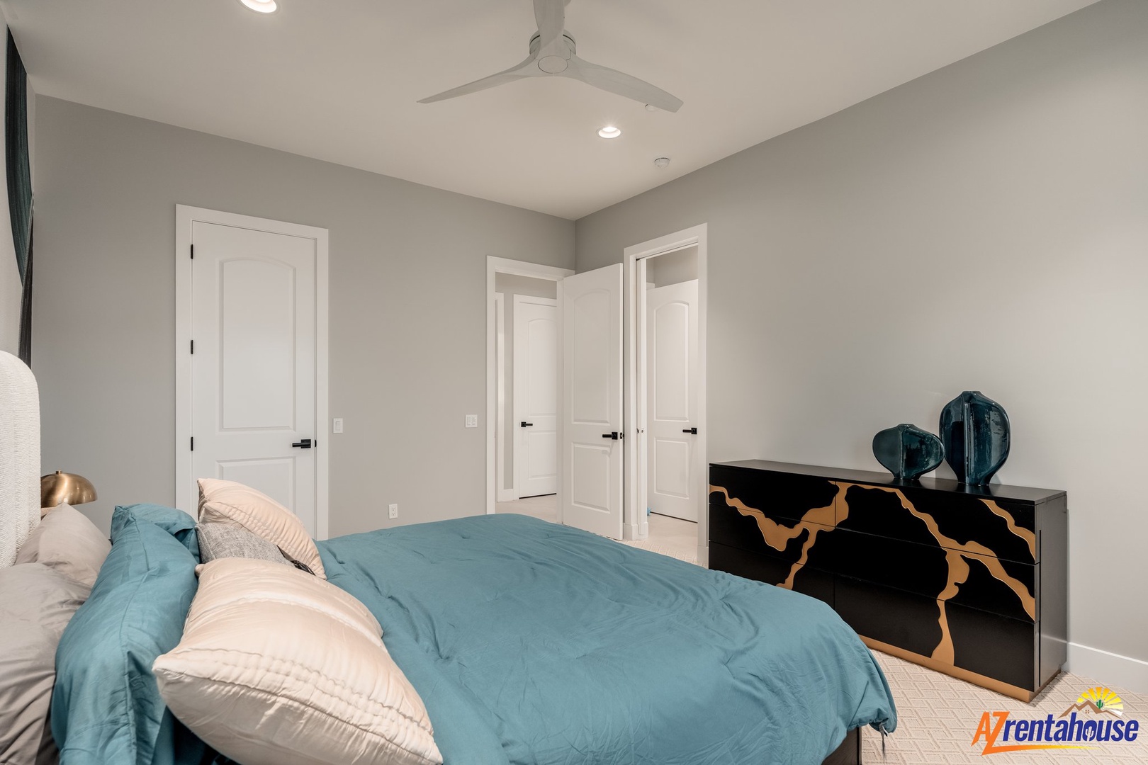 Your tranquil bedroom features soothing teal linens and a stylish gold-accented dresser, creating the perfect peaceful retreat.