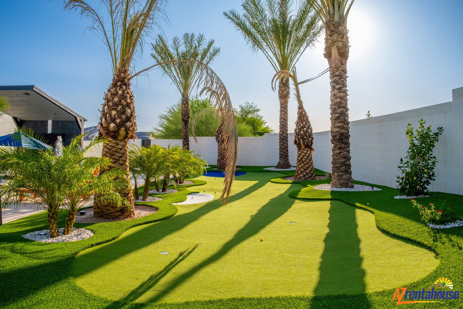 Private tropical oasis featuring a custom putting green surrounded by towering palm trees and lush landscaping for ultimate relaxation.