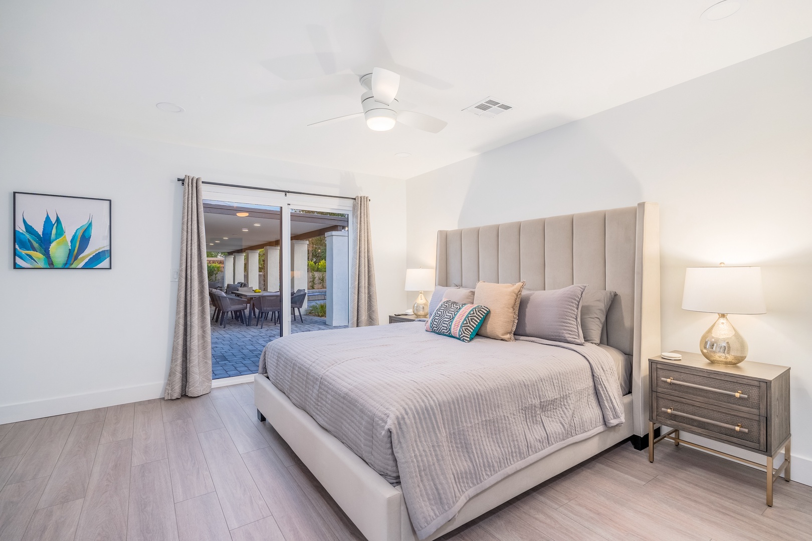 Step into your serene bedroom retreat with a plush bed, elegant furnishings, and glass doors opening to an inviting outdoor patio—your perfect space to unwind.