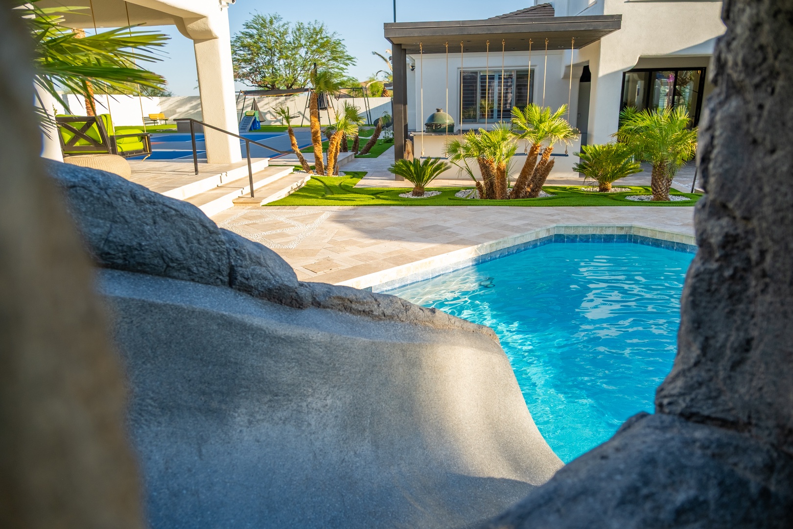 A sparkling pool framed by tropical palms invites you to unwind beneath the clear desert sky, your private oasis awaiting.