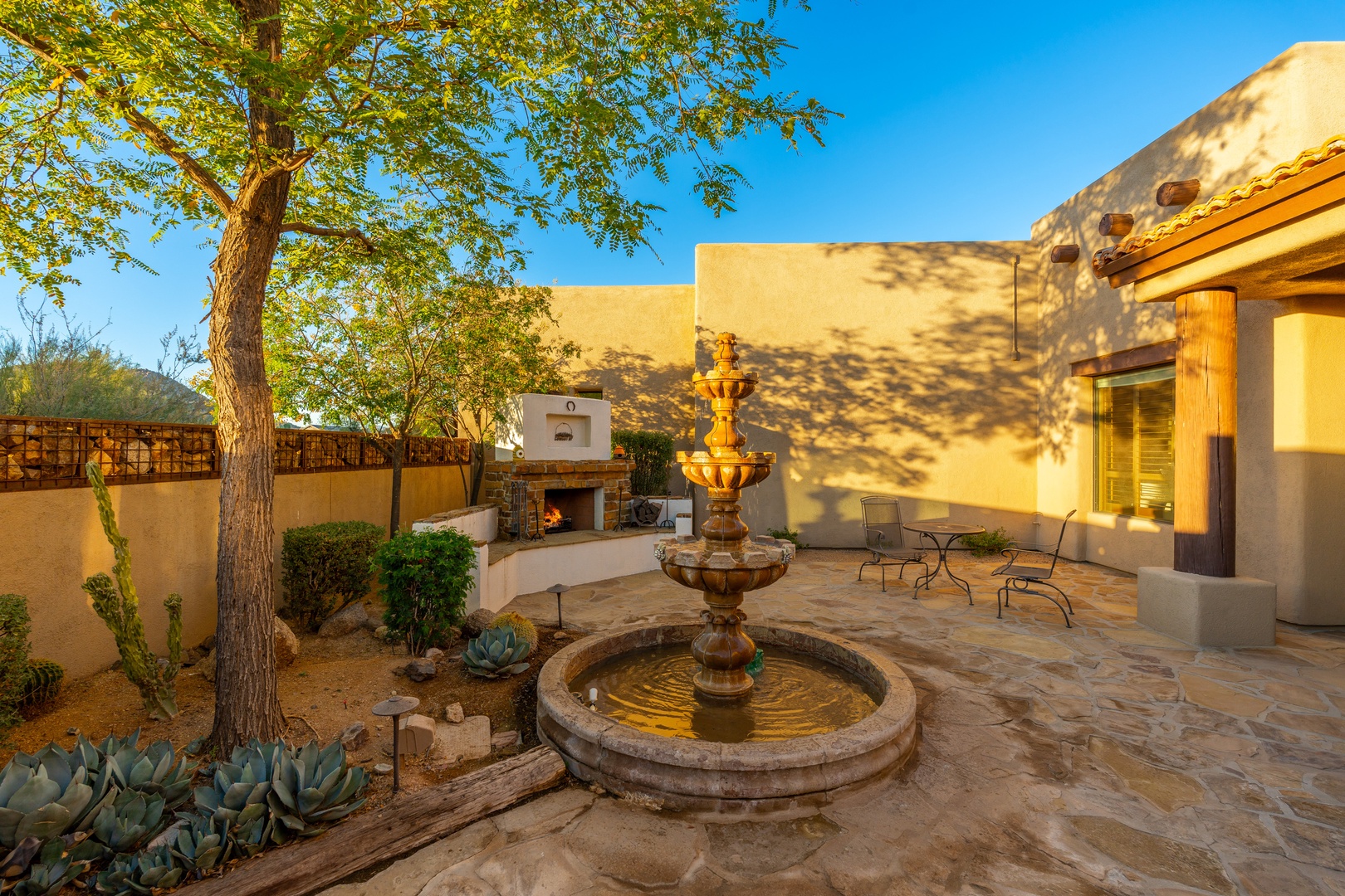 Step into your private courtyard sanctuary, where a tiered fountain sparkles beneath desert trees. Warm stone patios invite you to unwind by the outdoor fireplace and enjoy peaceful evenings under open skies.