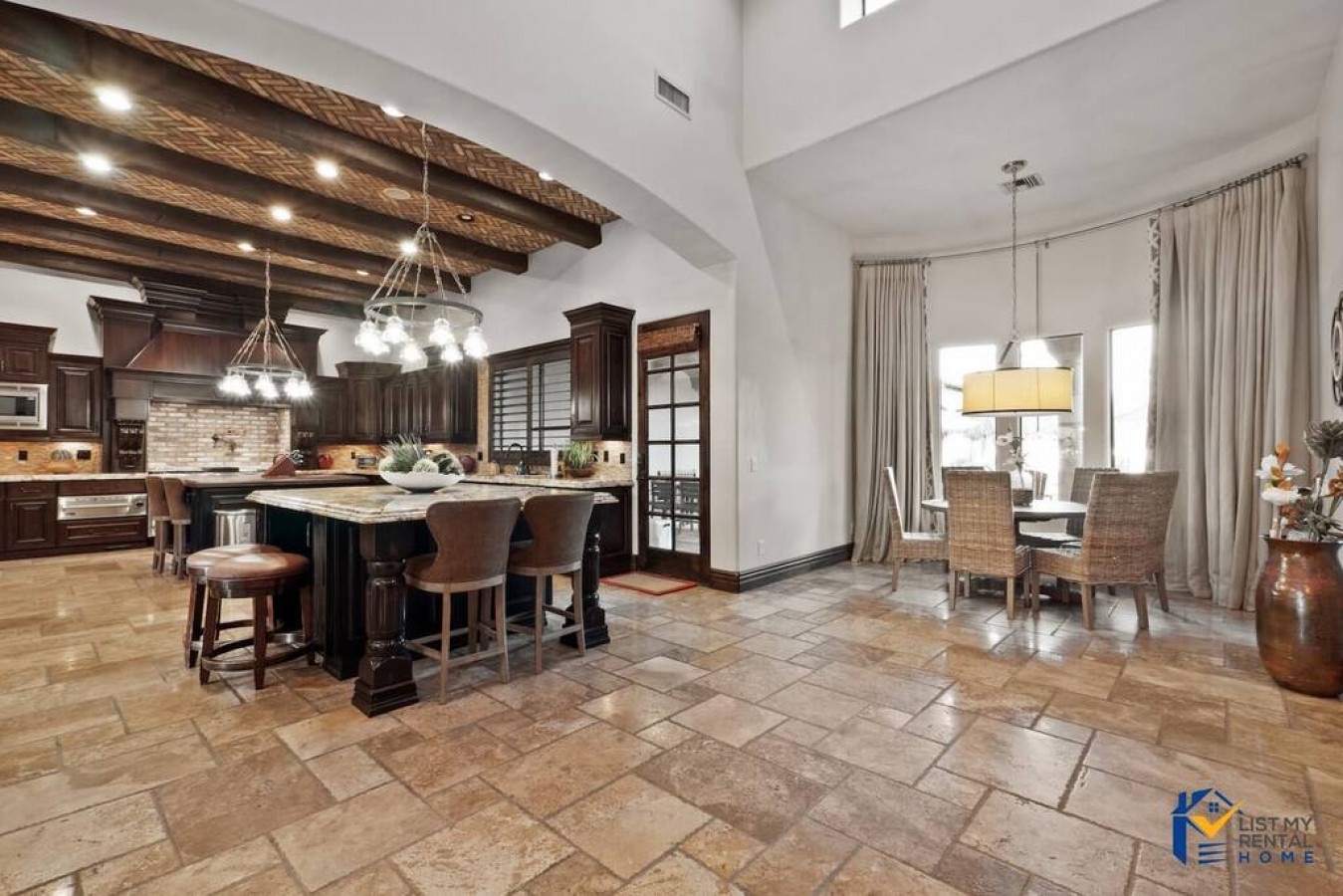Your gourmet kitchen flows seamlessly into elegant dining space with rustic beams, marble counters, and rich wood cabinetry perfect for memorable meals.